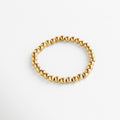 Detalle de pulsera dorada de cuentas grandes con acabado brillante, Pulsera dorada moderna con esferas metálicas grandes y pulidas.