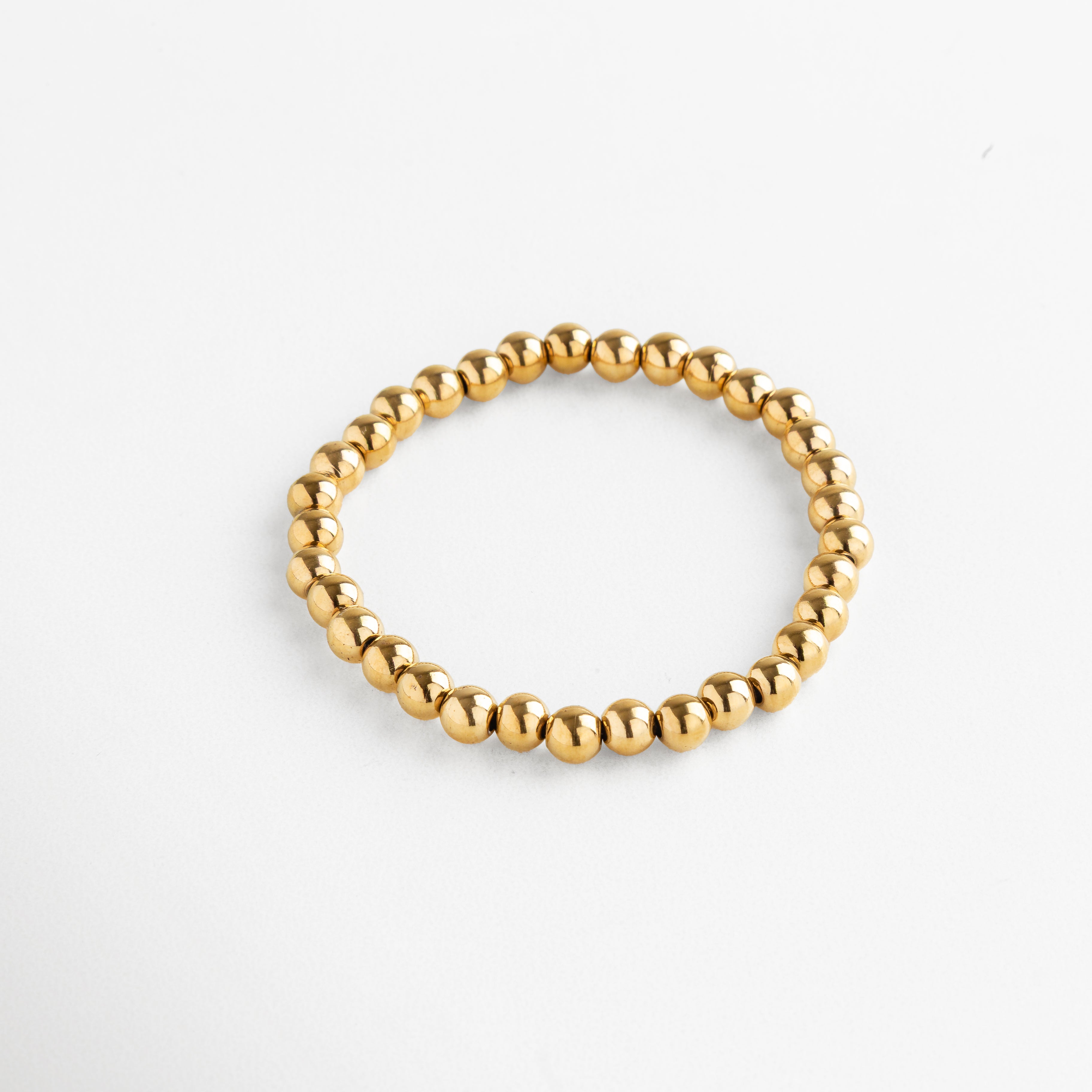 Detalle de pulsera dorada de cuentas grandes con acabado brillante, Pulsera dorada moderna con esferas metálicas grandes y pulidas.