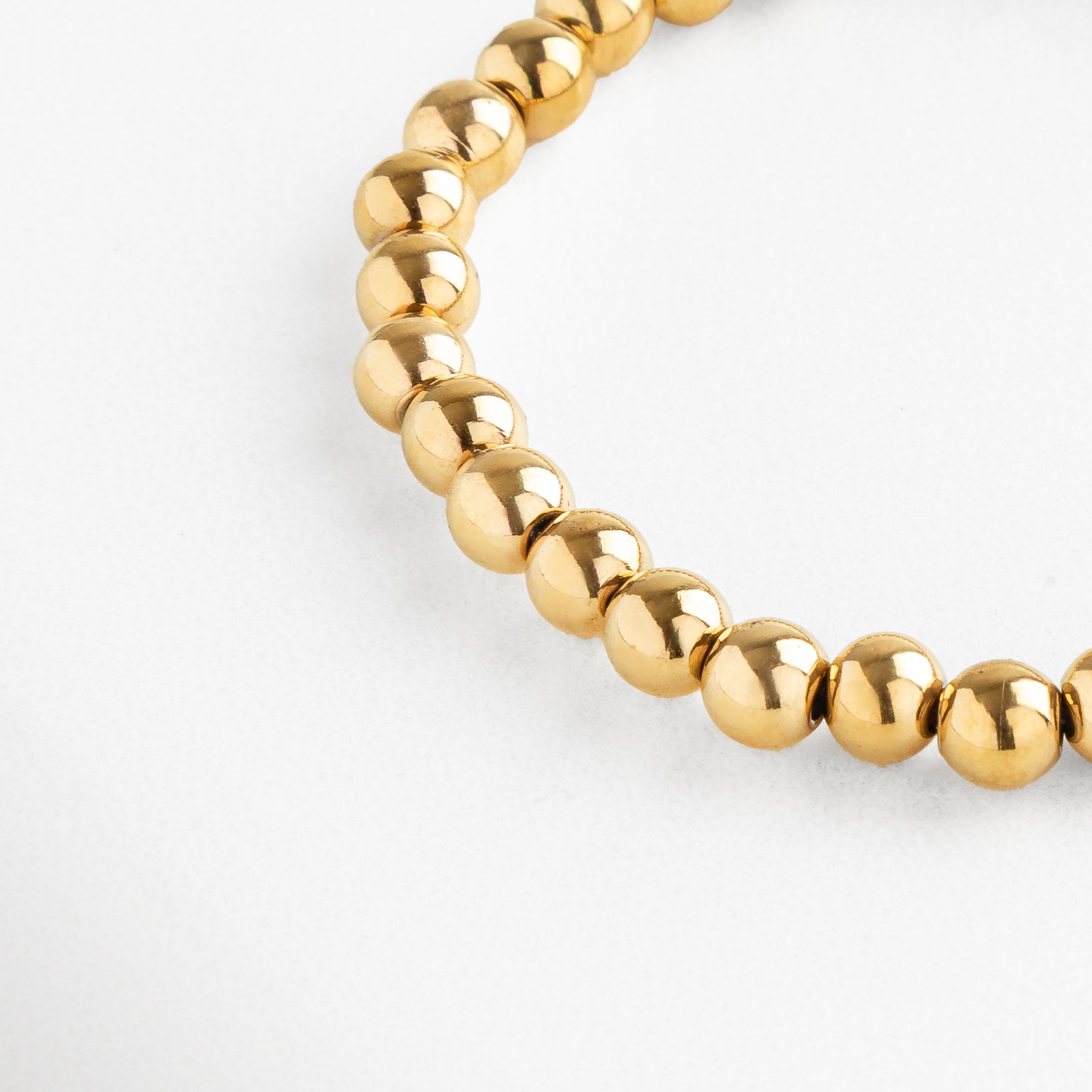 Detalle de pulsera dorada de cuentas grandes con acabado brillante, Pulsera dorada moderna con esferas metálicas grandes y pulidas.