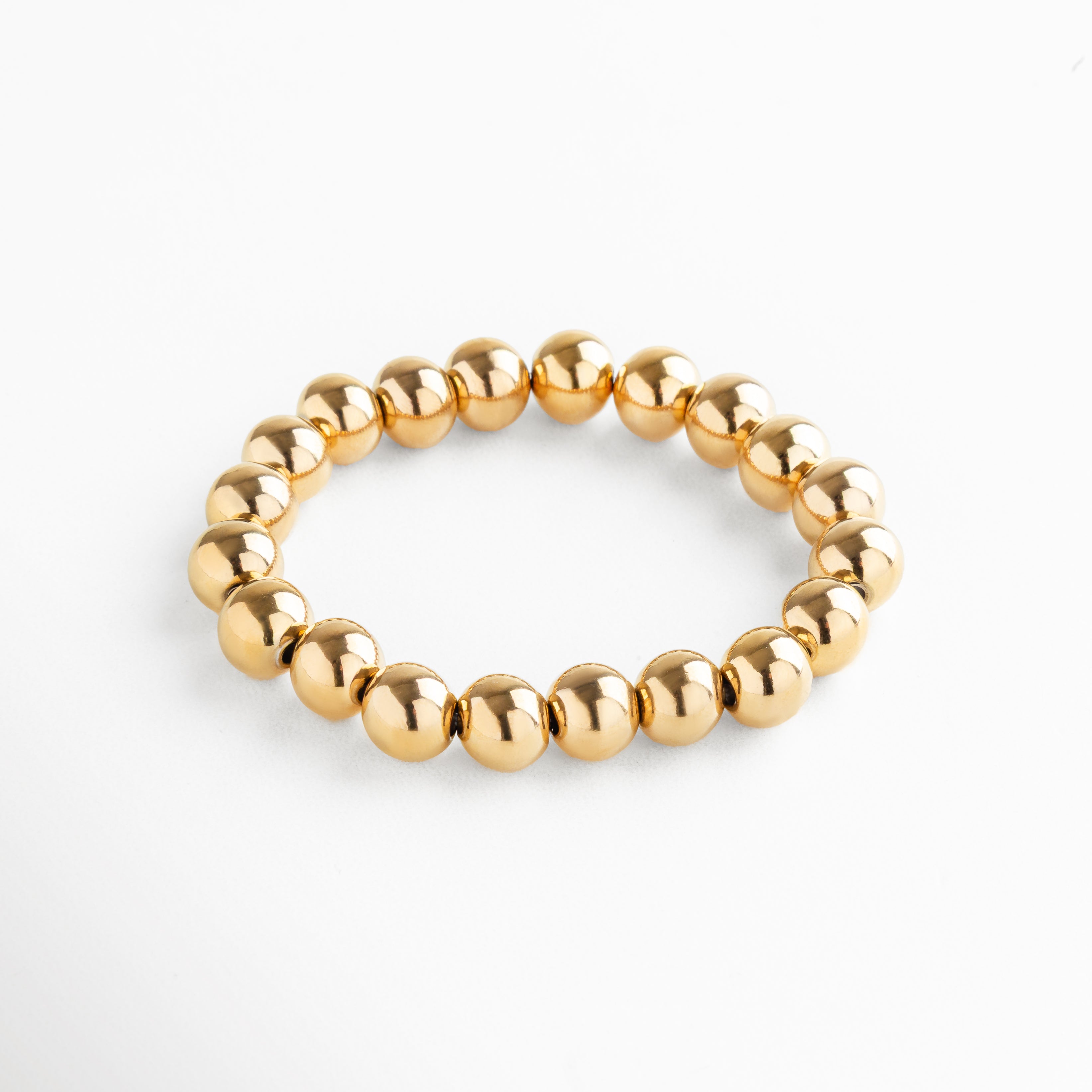 Pulsera elástica de cuentas grandes en acero inoxidable con baño de oro 18K, diseño minimalista y versátil ideal para usar sola o en capas.
