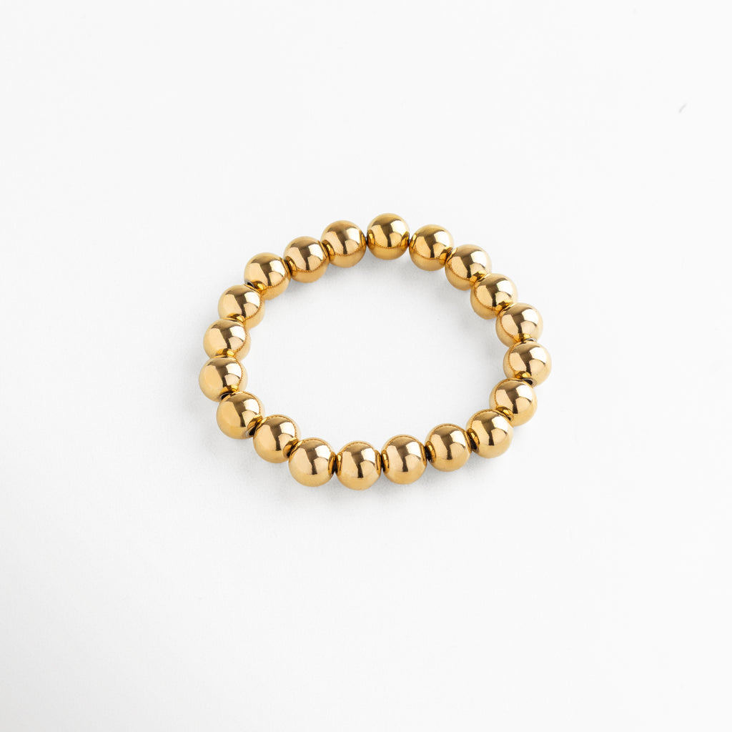 Pulsera elástica de cuentas metálicas doradas, diseño clásico y sofisticado, pieza versátil para un estilo elegante y effortless.