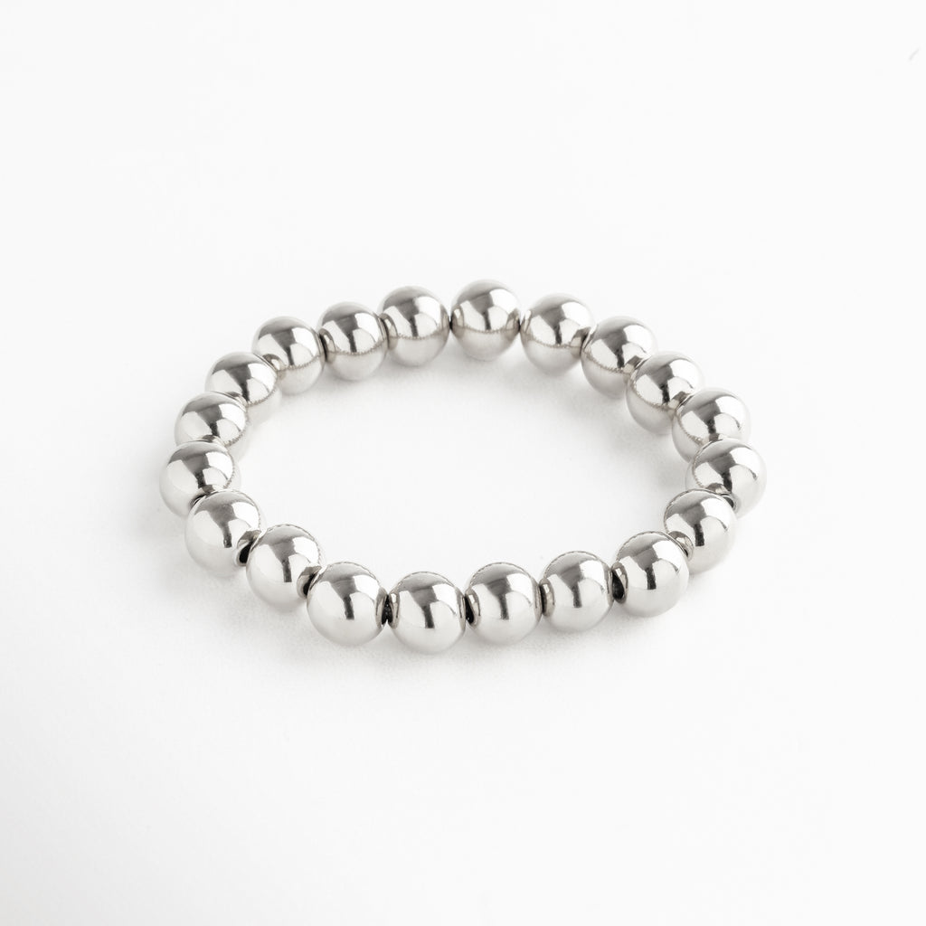 Pulsera elástica de cuentas grandes en acero inoxidable con baño de oro blanco 18K, diseño minimalista y versátil ideal para usar sola o en capas.