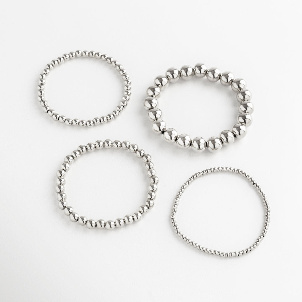 set de pulseras plateadas con cuentas en varios tamaños, incluye pulsera mediana, Conjunto de pulseras plateadas apilables, diseño minimalista con cuentas medianas.