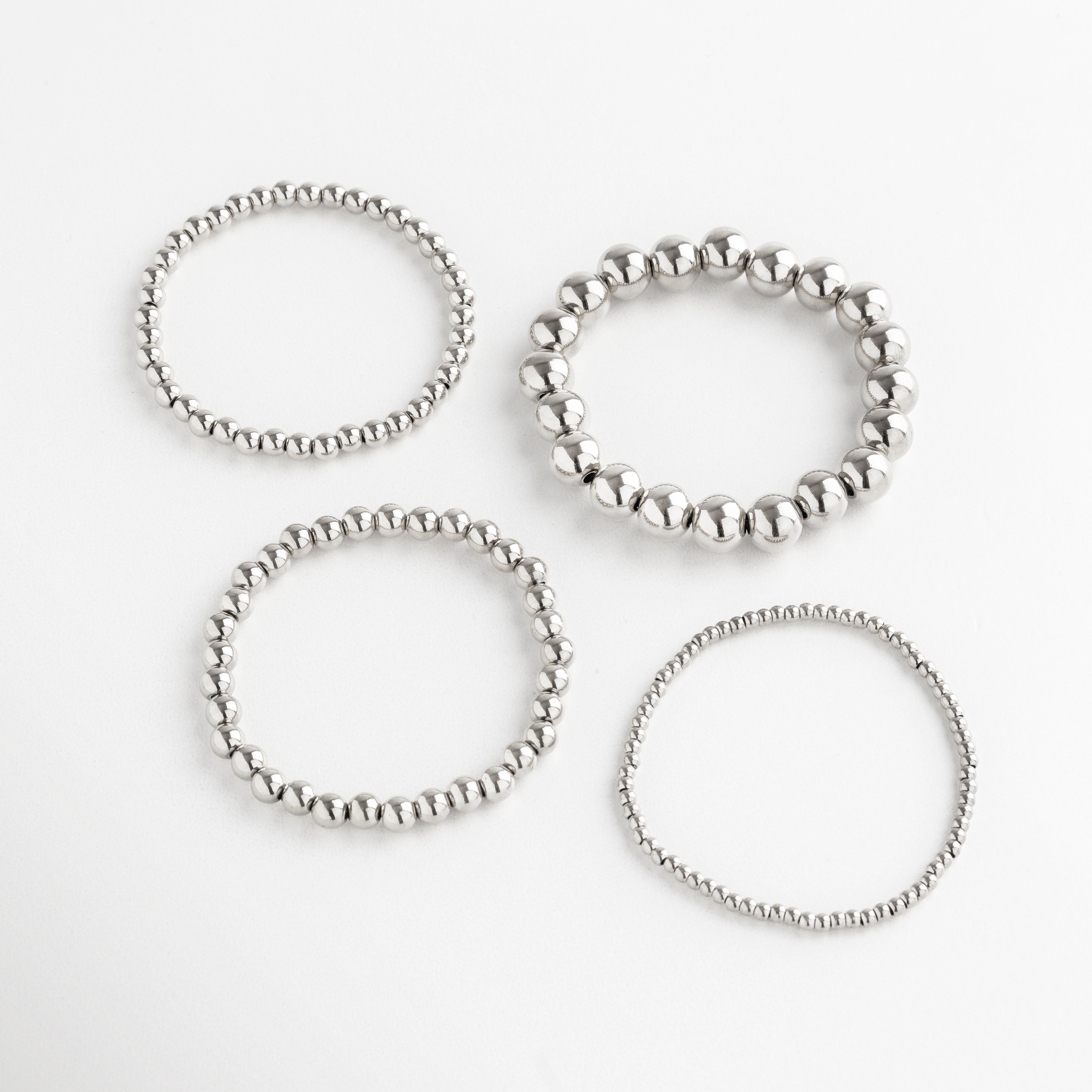 set de pulseras plateadas con cuentas en varios tamaños, incluye pulsera mediana, Conjunto de pulseras plateadas apilables, diseño minimalista con cuentas medianas.