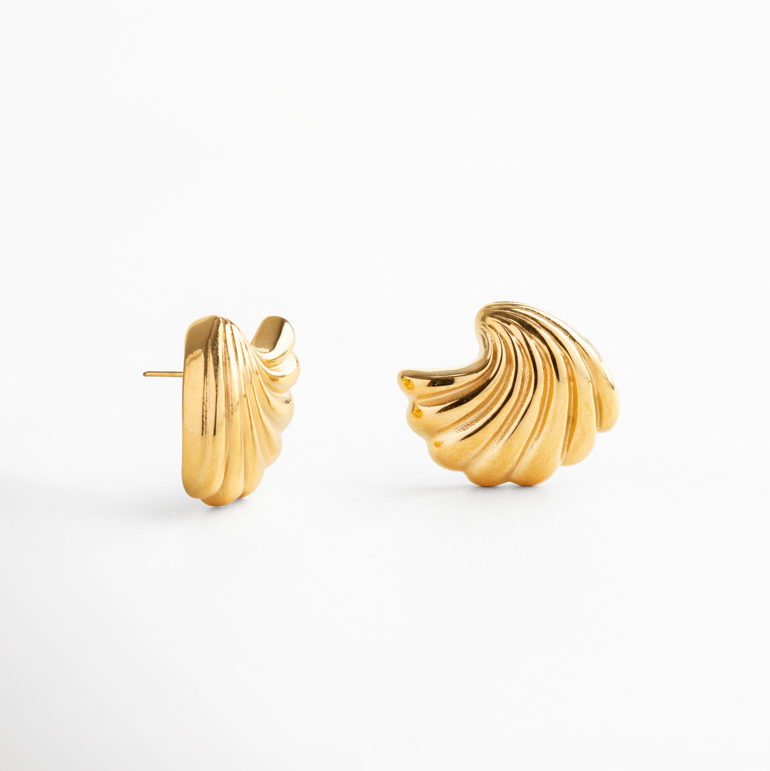 textura pulida con acabado dorado brillante, diseño envolvente que refleja movimiento, superficie lisa y uniforme, estética moderna y minimalista, aretes ligeros y cómodos