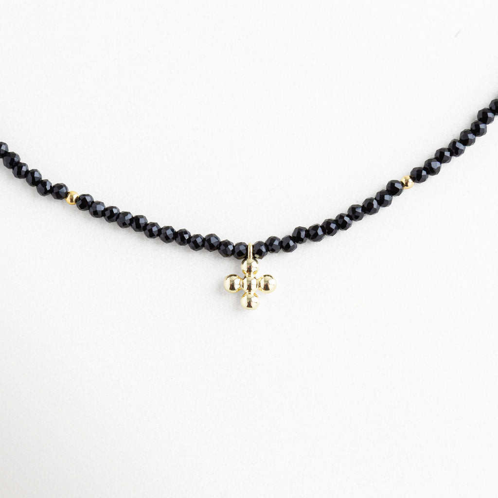 Collar negro con cuentas brillantes y dije dorado en forma esférica, joya delicada con baño de oro 18K, ideal para un look elegante y atemporal.