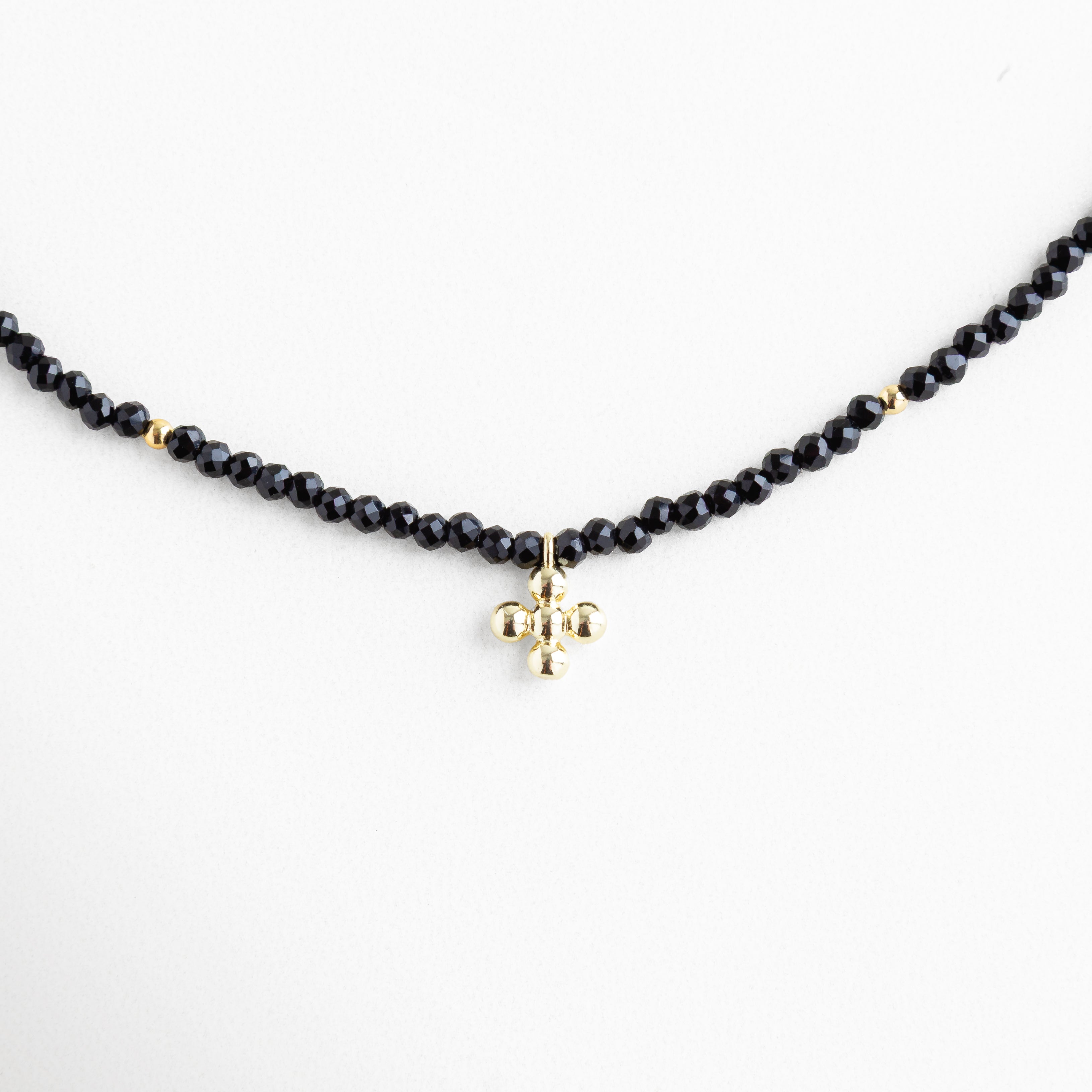 Collar negro con cuentas brillantes y dije dorado en forma esférica, joya delicada con baño de oro 18K, ideal para un look elegante y atemporal.