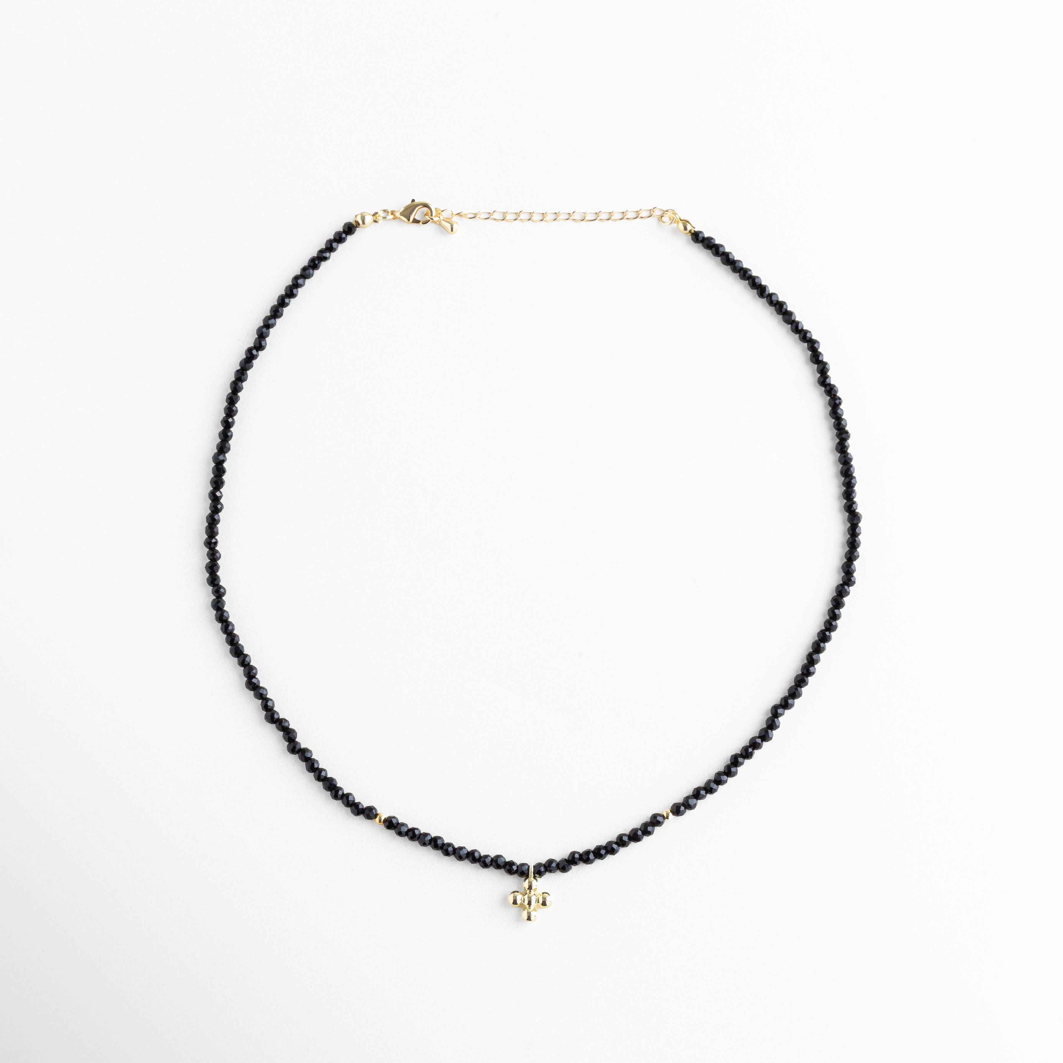 Collar corto de cuentas negras con dije dorado, cristales sintéticos y baño en oro 18K, accesorio versátil para looks casuales y sofisticados.