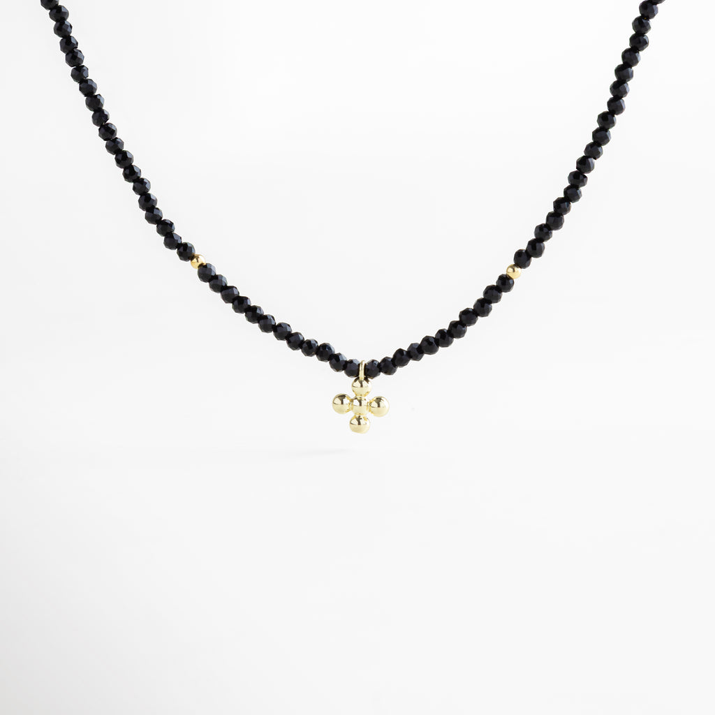 Collar negro con dije en dorado, cuentas facetadas brillantes y acentos en oro 18K, pieza versátil que equilibra lo moderno con lo clásico.