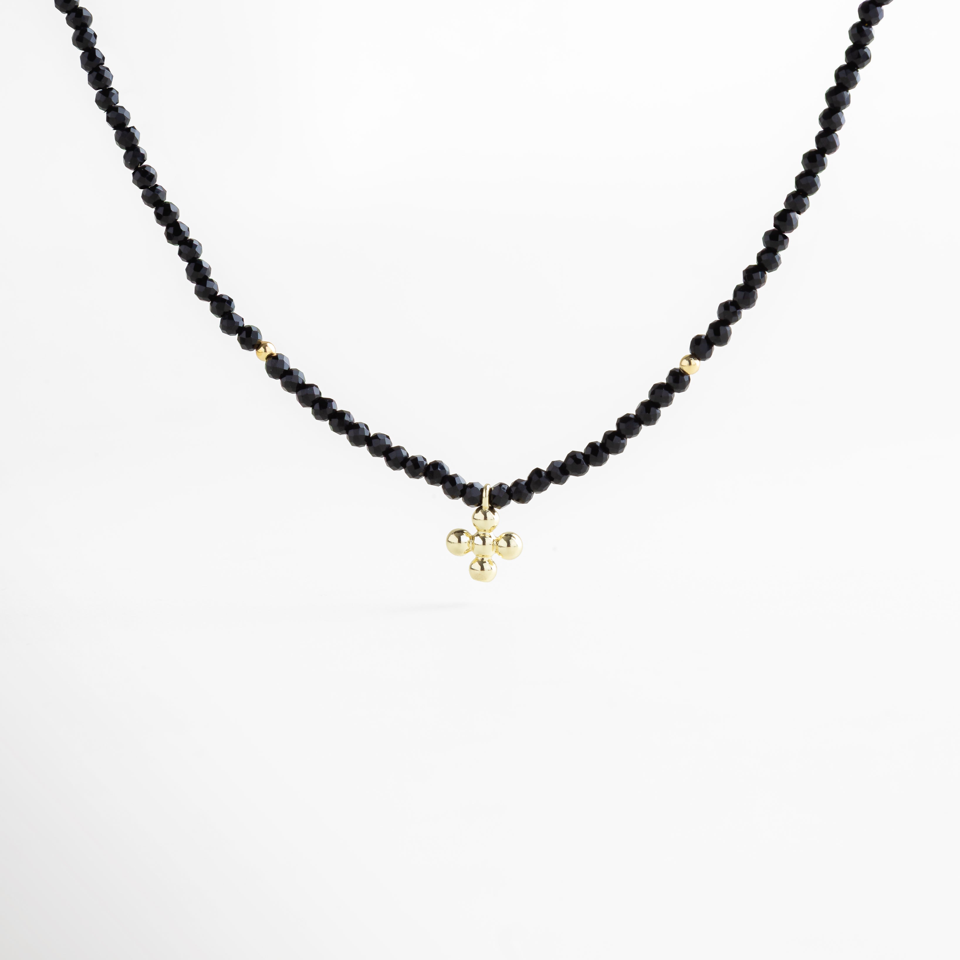 Collar negro con dije en dorado, cuentas facetadas brillantes y acentos en oro 18K, pieza versátil que equilibra lo moderno con lo clásico.