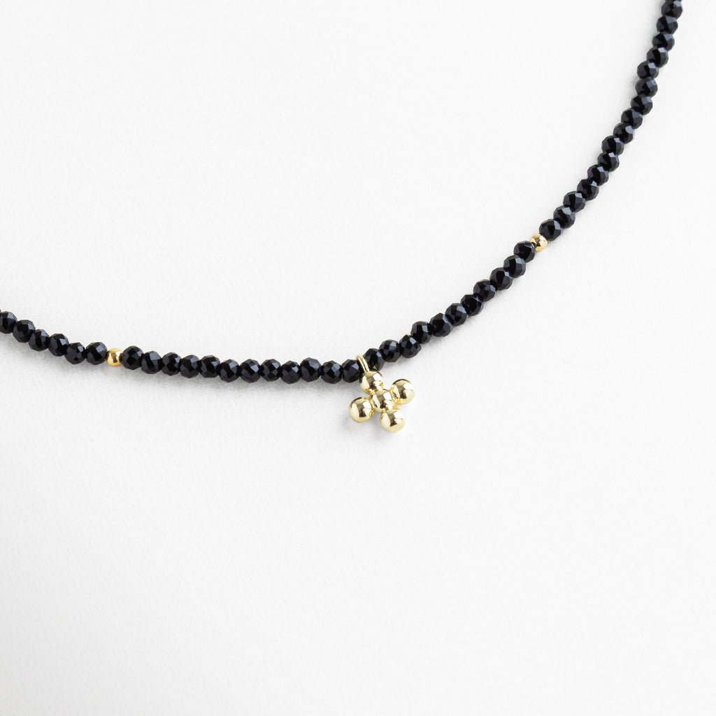 Collar de cuentas negras con dije dorado minimalista, cristal sintético y baño en oro 18K, diseño elegante y moderno para uso diario o de noche.