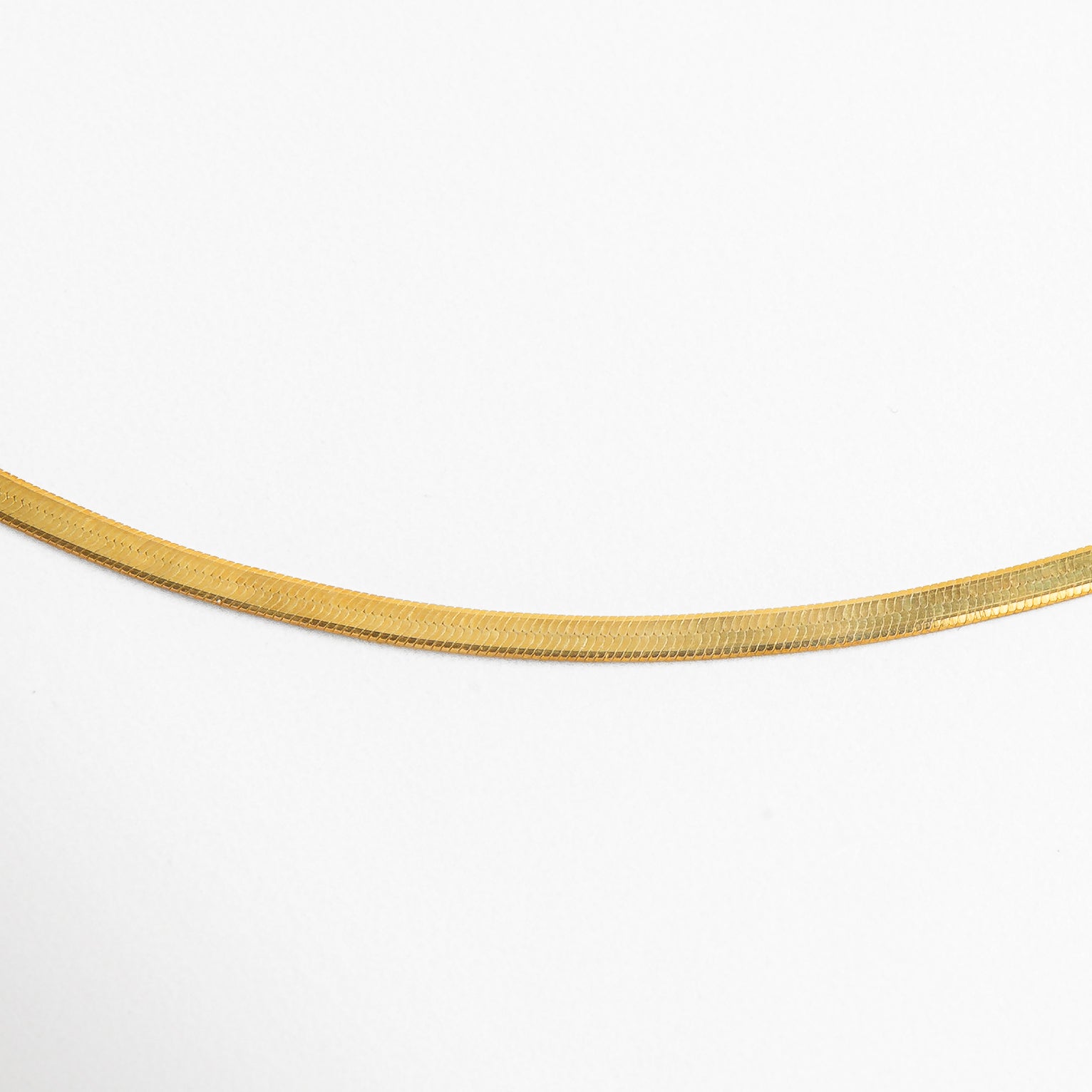 Detalle del acabado planchado del Collar Pressed Golden Aída dorado, mostrando el brillo uniforme de su superficie. Close-up de la cadena dorada con textura lisa y delgada, resaltando su elegancia discreta. Zoom al collar dorado con acabado planchado, con eslabones planos y estructura pulida. Detalle cercano del collar de plata 925 enchapado en oro, con diseño minimalista. Primer plano de la textura planchada del Collar Aída, capturando su efecto espejo y estilo moderno.