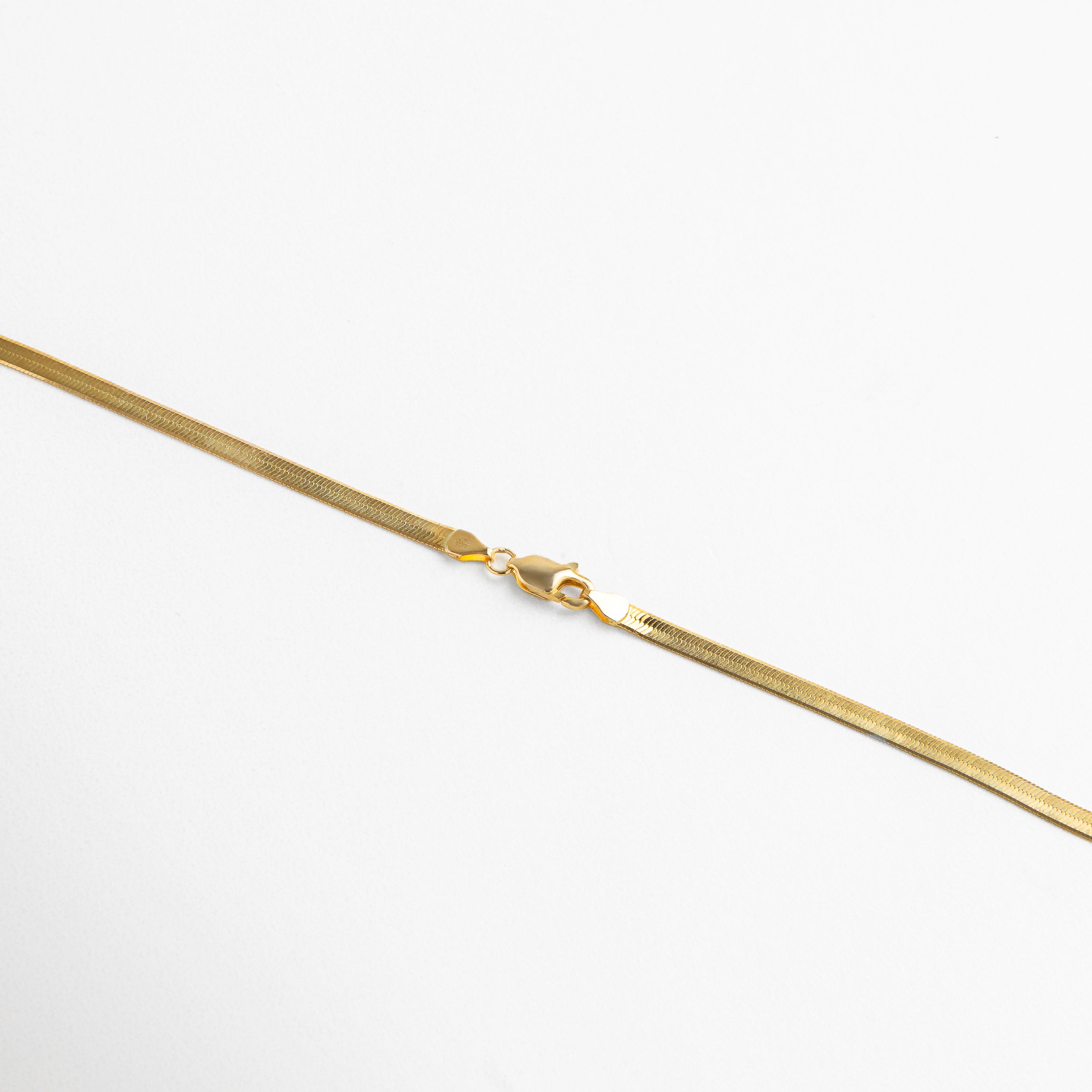 Collar Pressed Golden Aída dorado visto de perfil, con grosor delgado de 0.3 cm y caída elegante. Vista lateral del collar con acabado plano, mostrando su estructura fina y fluida. Perfil del collar dorado de 40 + 6 cm de longitud, ideal para un look refinado y versátil. Detalle lateral del collar planchado en tono dorado, con movimiento sutil y textura suave. Collar dorado visto desde un ángulo lateral, resaltando su diseño plano y acabado brillante