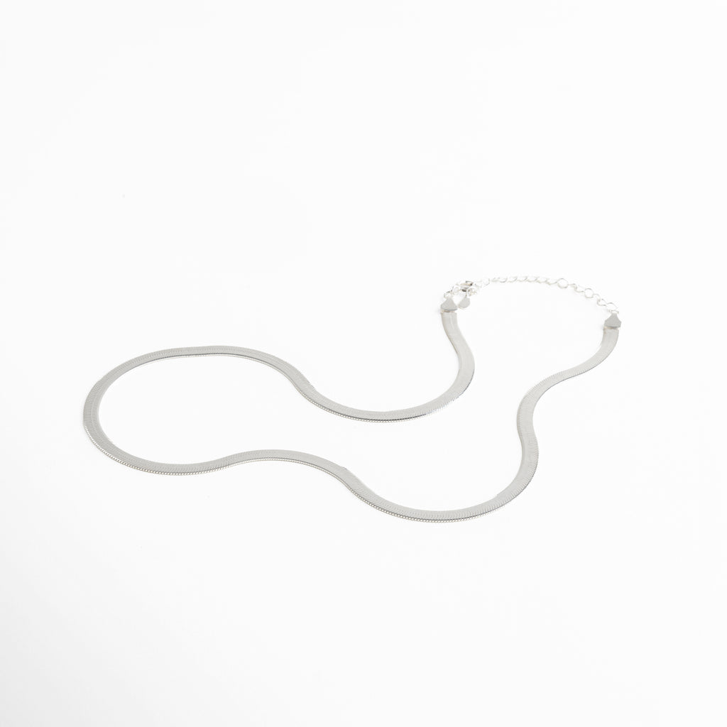 Collar Pressed Silver Aída visto de perfil, mostrando su grosor delgado y caída uniforme. Vista lateral del collar plateado, resaltando su acabado planchado y líneas limpias. Perfil del collar minimalista en plata, diseño elegante y discreto. Detalle lateral del collar Pressed Silver Aída, mostrando su estructura ligera y pulida. Collar plateado visto desde un ángulo lateral, diseño versátil y acabado reflectivo.