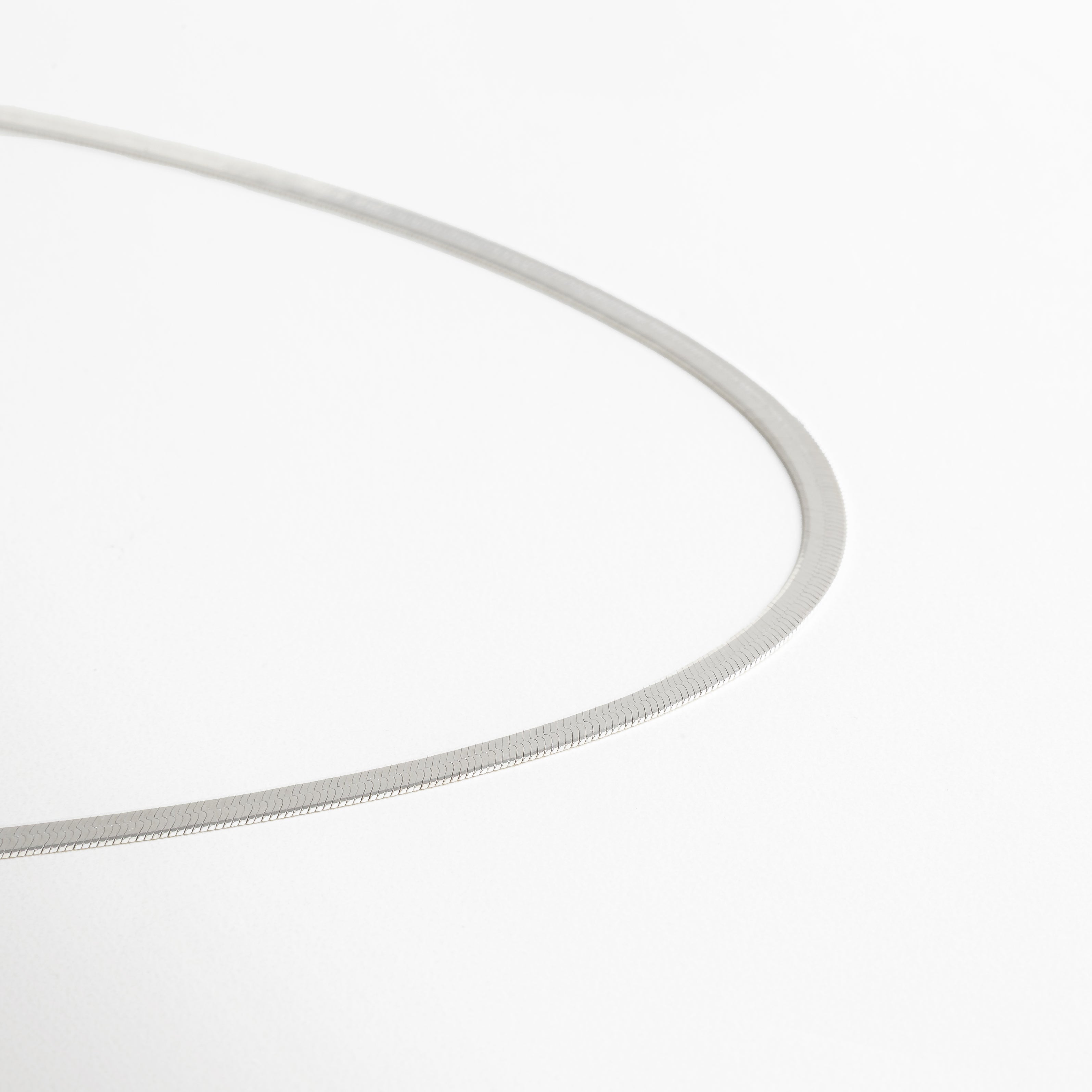 Collar Pressed Silver Aída visto de perfil, mostrando su grosor delgado y caída uniforme. Vista lateral del collar plateado, resaltando su acabado planchado y líneas limpias. Perfil del collar minimalista en plata, diseño elegante y discreto. Detalle lateral del collar Pressed Silver Aída, mostrando su estructura ligera y pulida. Collar plateado visto desde un ángulo lateral, diseño versátil y acabado reflectivo.