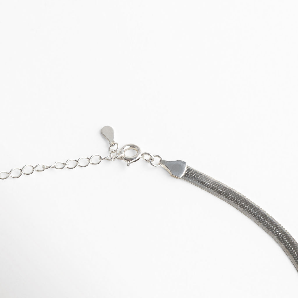 Collar Pressed Silver Aída visto de perfil, mostrando su grosor delgado y caída uniforme. Vista lateral del collar plateado, resaltando su acabado planchado y líneas limpias. Perfil del collar minimalista en plata, diseño elegante y discreto. Detalle lateral del collar Pressed Silver Aída, mostrando su estructura ligera y pulida. Collar plateado visto desde un ángulo lateral, diseño versátil y acabado reflectivo.