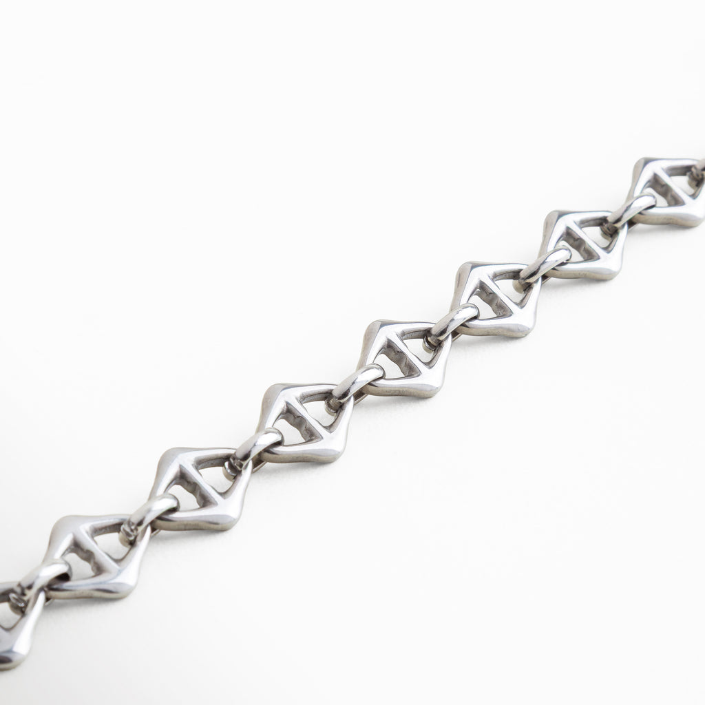 "Vista cercana de los eslabones geométricos de la Pulsera Silver Amina en acero inoxidable con recubrimiento en oro blanco 18K, pulsera de 0.8 cm de ancho con estilo único, combinación de fuerza y sofisticación en cada detalle del diseño."
