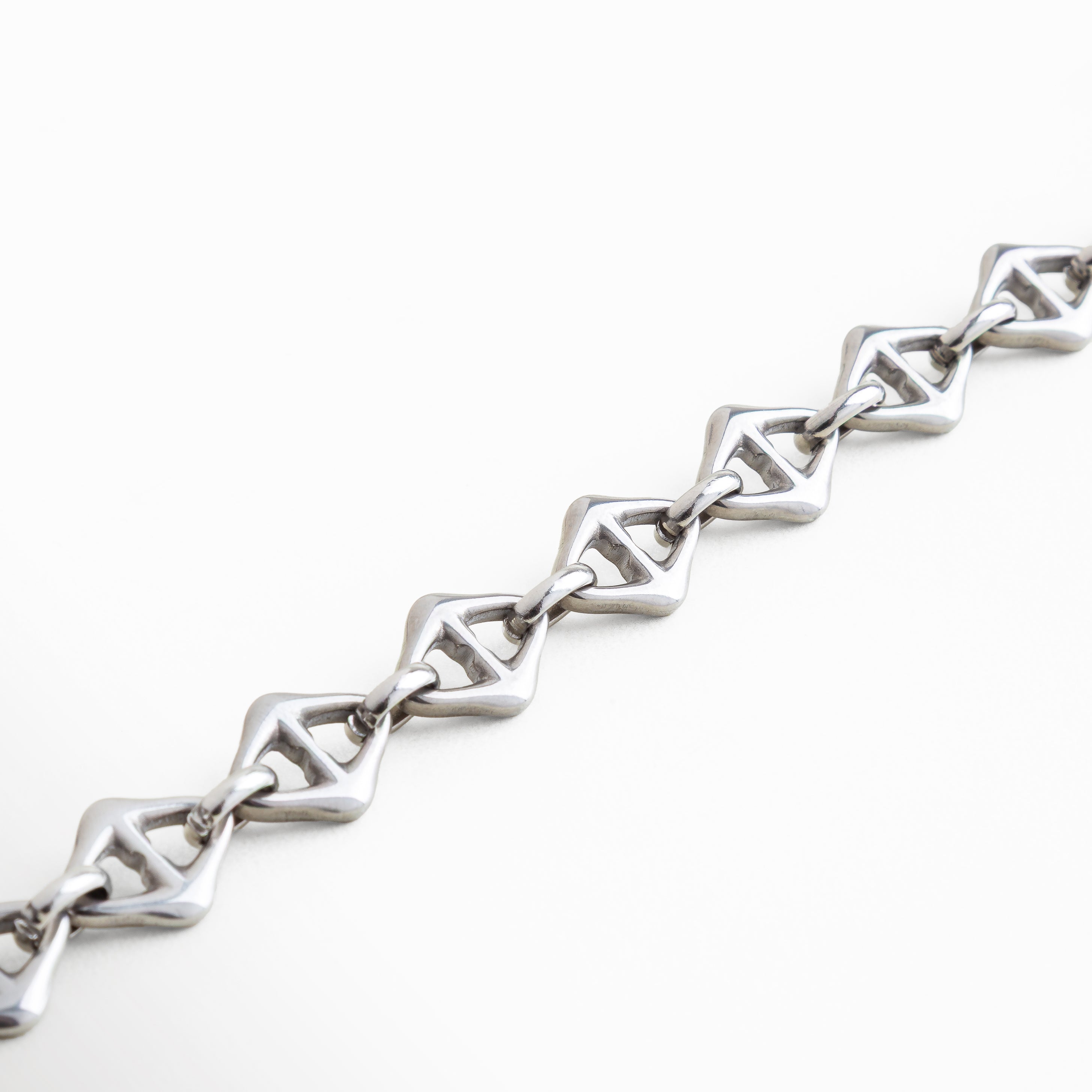 "Vista cercana de los eslabones geométricos de la Pulsera Silver Amina en acero inoxidable con recubrimiento en oro blanco 18K, pulsera de 0.8 cm de ancho con estilo único, combinación de fuerza y sofisticación en cada detalle del diseño."