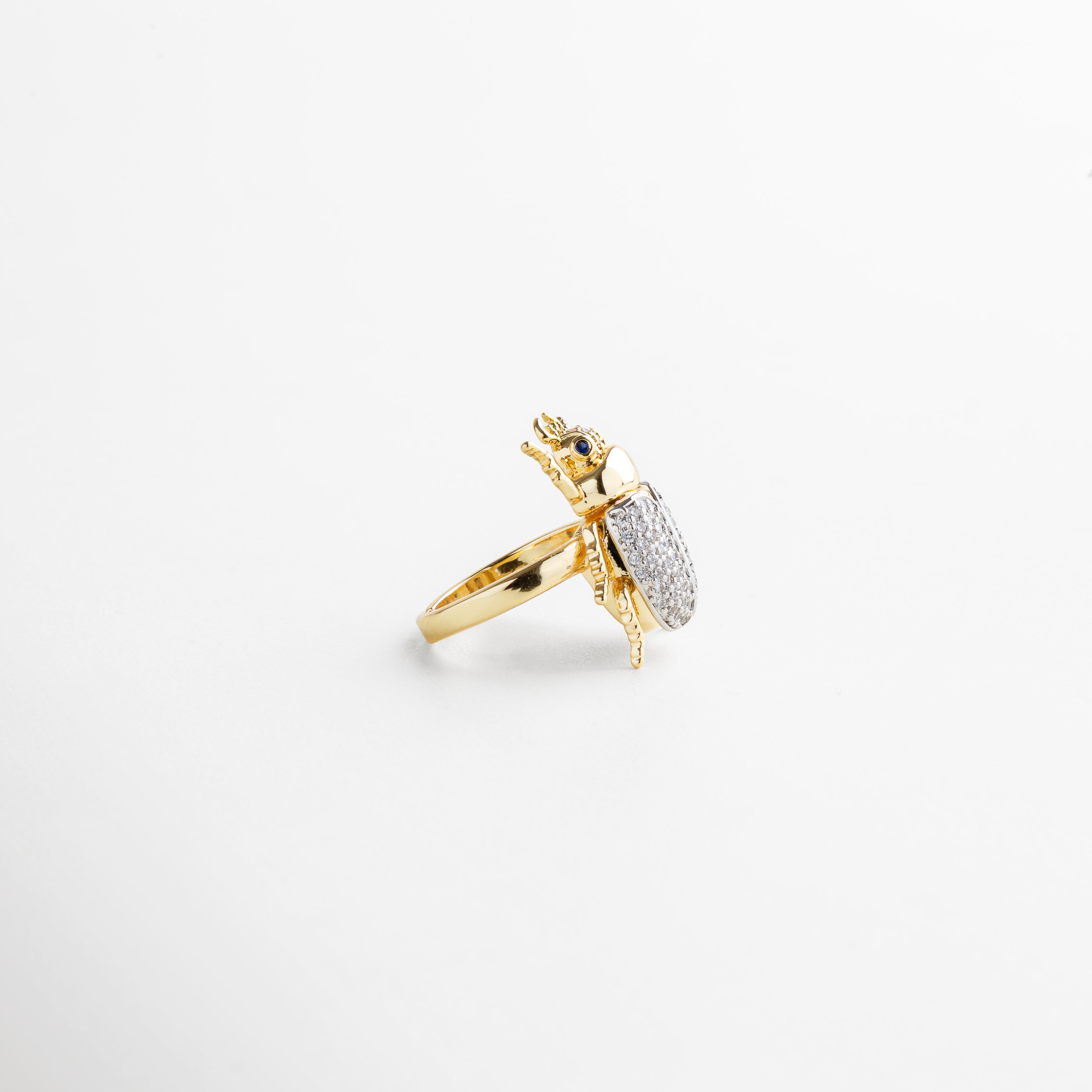 perfil lateral del anillo mostrando la forma del escarabajo, grosor del aro consistente, interior liso para mayor comodidad, engaste seguro de las piedras, acabado dorado brillante y duradero