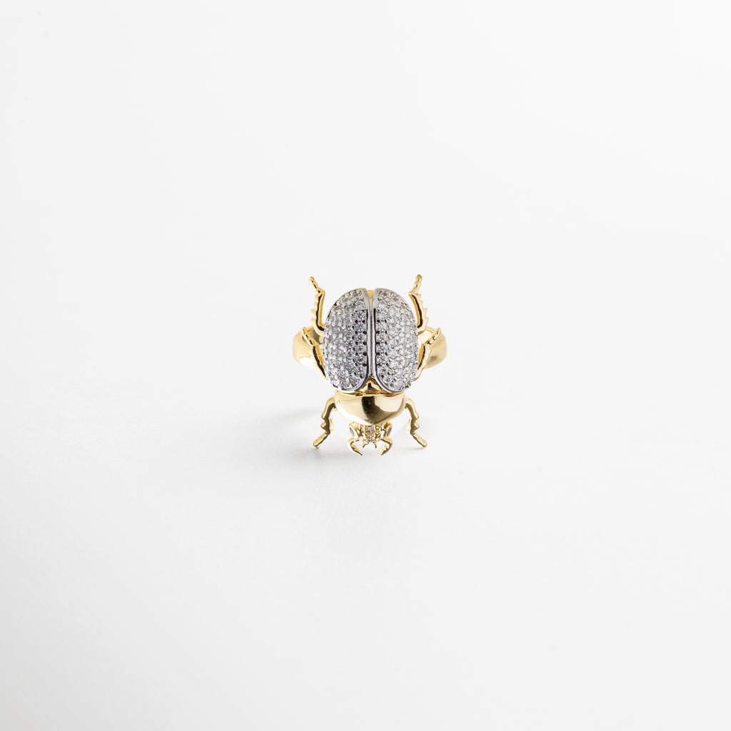 combinación de diseño artístico y minimalismo, zirconias que capturan la luz, proporción equilibrada entre escarabajo y aro, detalle sofisticado y llamativo, pieza versátil para distintos estilos
