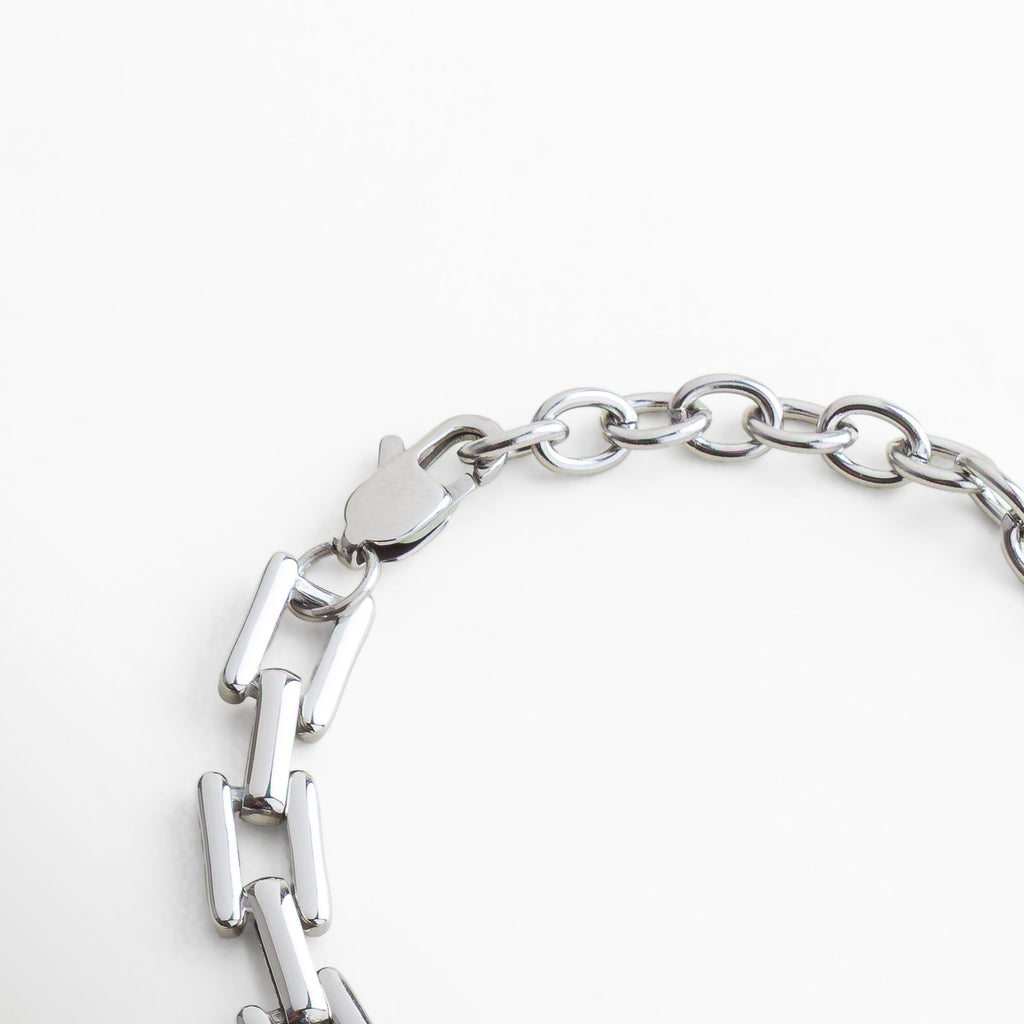 Detalle de broche de pulsera plateada en acero inoxidable, acabado en oro blanco 18K con eslabones modernos, diseño seguro y duradero para uso diario.