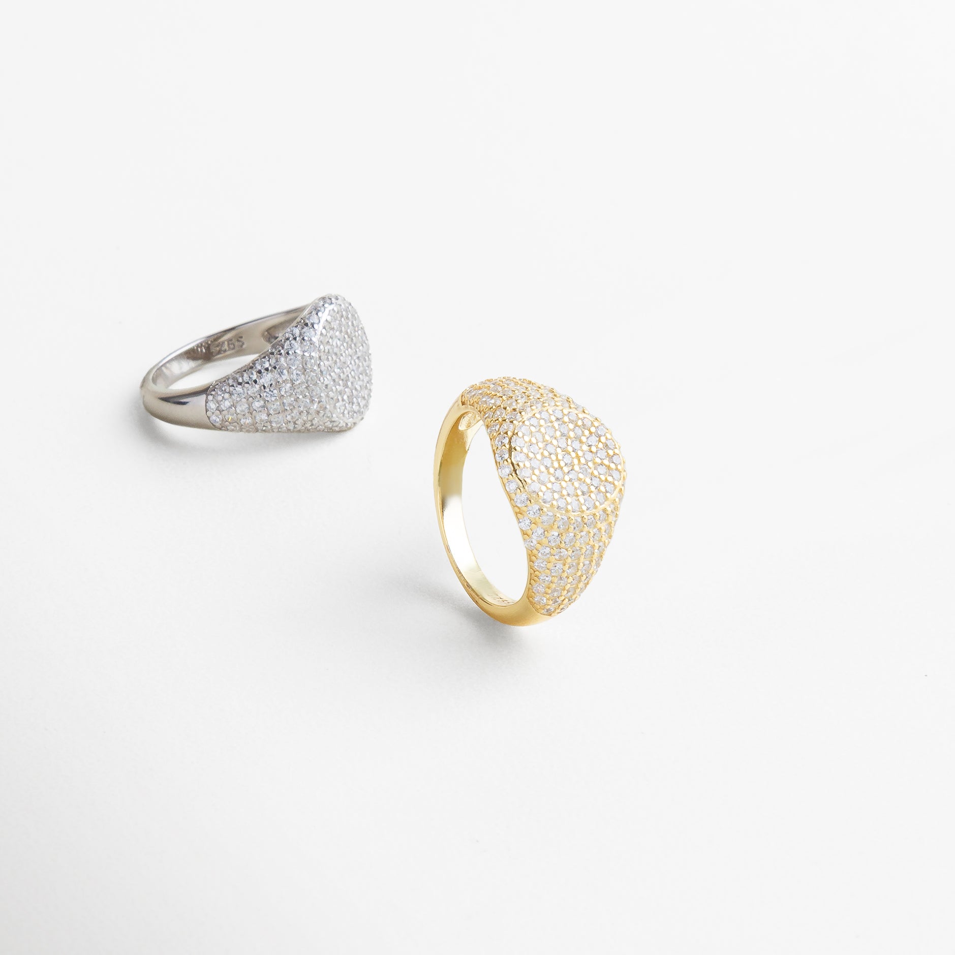 Vista lateral del Anillo Golden Idriss dorado, mostrando la altura de su diseño y el efecto de las zirconias desde el perfil. Anillo dorado visto de lado, con acabado pulido y destellos de zirconia en una estructura elegante. Perfil del anillo con incrustaciones brillantes en tono dorado, ideal para estilos modernos y clásicos. Detalle lateral del Anillo Golden Idriss dorado, con forma curva de 2.5 cm y brillo sutil. Anillo en acabado dorado visto desde el lateral, combinando sofisticación y