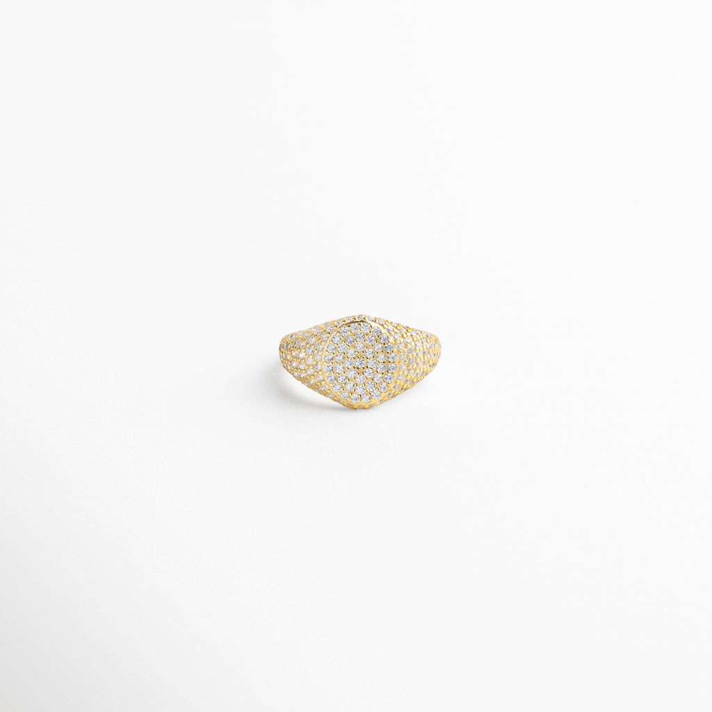 Vista superior del Anillo Golden Idriss dorado, con detalles en zirconia sobre superficie brillante de 2.5 cm. Toma cenital del anillo con incrustaciones brillantes en dorado, destacando su forma elegante y delicada. Anillo dorado visto desde arriba, con zirconias perfectamente distribuidas en un diseño refinado. Perspectiva superior del anillo de plata 925 con baño dorado e incrustaciones que capturan la luz. Vista desde arriba del Anillo Golden Idriss, resaltando su silueta alargada y bril