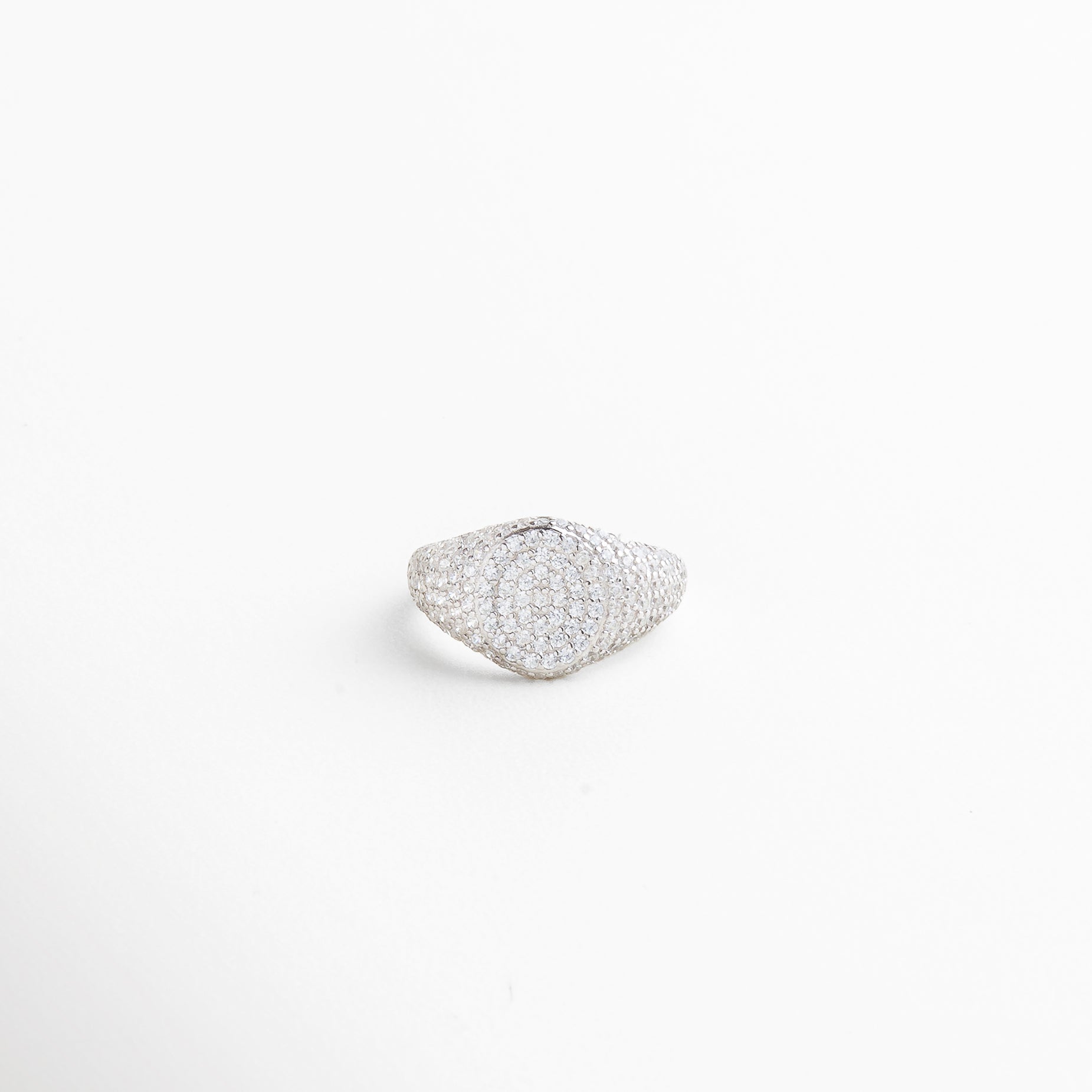 Vista superior del Anillo Idriss plateado, con diseño de 2.5 cm lleno de brillo gracias a sus zirconias incrustadas. Toma cenital del anillo en acabado plateado, con detalles que evocan elegancia clásica y moderna. Anillo de plata 925 con zirconias visto desde arriba, mostrando su forma estilizada y brillante. Perspectiva superior del Anillo Idriss plateado, con distribución armoniosa de las piedras brillantes. Vista desde arriba del anillo plateado, con forma alargada y acabado relucient