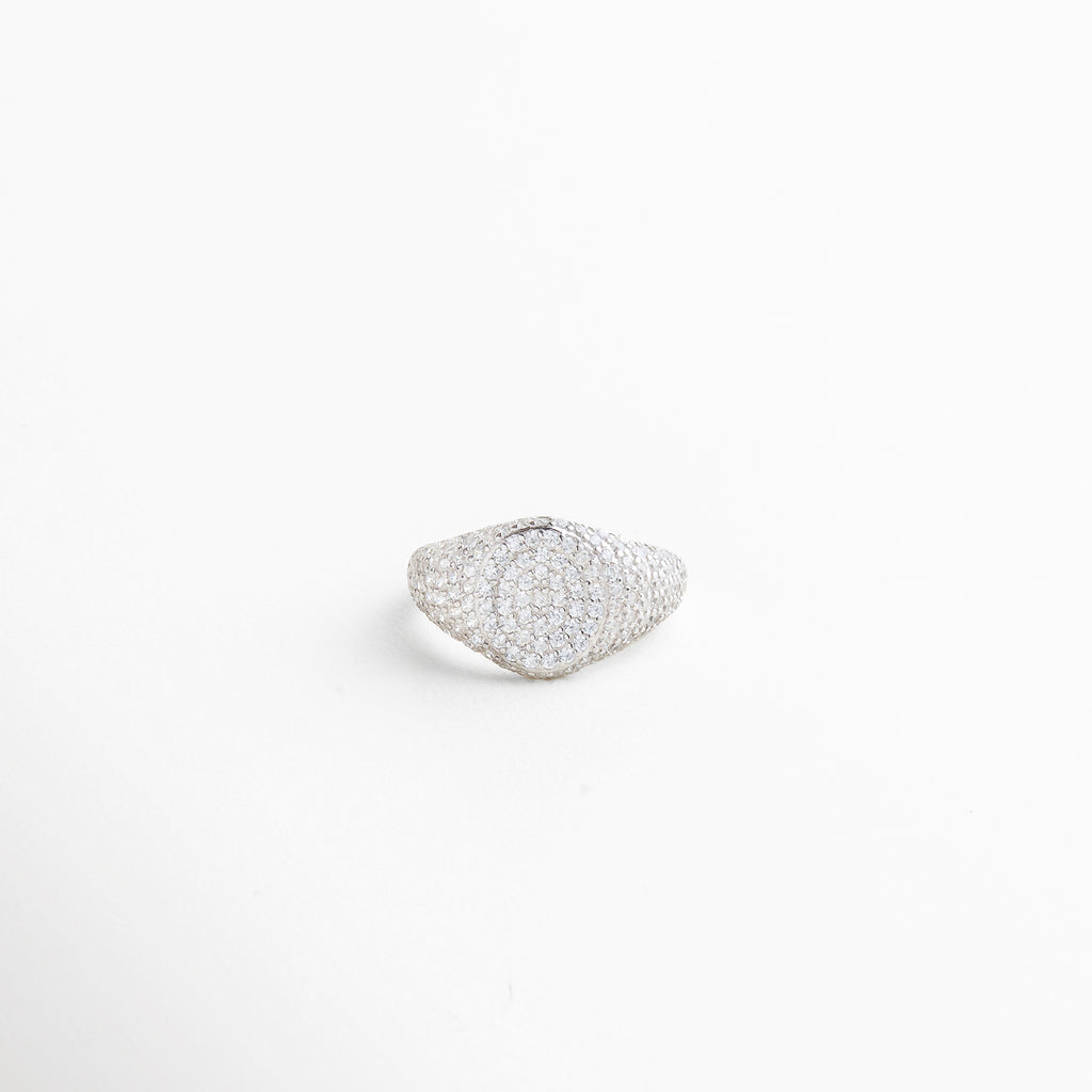 Vista superior del Anillo Idriss plateado, con diseño de 2.5 cm lleno de brillo gracias a sus zirconias incrustadas. Toma cenital del anillo en acabado plateado, con detalles que evocan elegancia clásica y moderna. Anillo de plata 925 con zirconias visto desde arriba, mostrando su forma estilizada y brillante. Perspectiva superior del Anillo Idriss plateado, con distribución armoniosa de las piedras brillantes. Vista desde arriba del anillo plateado, con forma alargada y acabado relucient