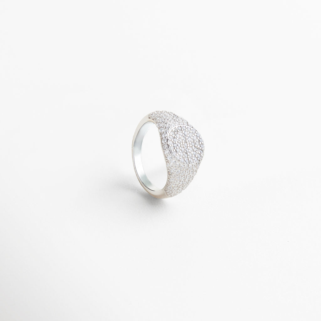 Anillo Idriss plateado visto desde el frente, con detalles brillantes de zirconia sobre estructura elegante. Vista frontal del anillo plateado con diseño alargado y detalles finos que reflejan la luz. Primer plano del Anillo Idriss en plata 925, con incrustaciones brillantes y estilo atemporal. Anillo plateado con zirconias visto de frente, ideal para llevar solo o combinado con otras piezas. Frontal del anillo Idriss plateado, con diseño sofisticado y luminosidad sutil.