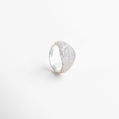 Anillo Idriss plateado visto desde el frente, con detalles brillantes de zirconia sobre estructura elegante. Vista frontal del anillo plateado con diseño alargado y detalles finos que reflejan la luz. Primer plano del Anillo Idriss en plata 925, con incrustaciones brillantes y estilo atemporal. Anillo plateado con zirconias visto de frente, ideal para llevar solo o combinado con otras piezas. Frontal del anillo Idriss plateado, con diseño sofisticado y luminosidad sutil.