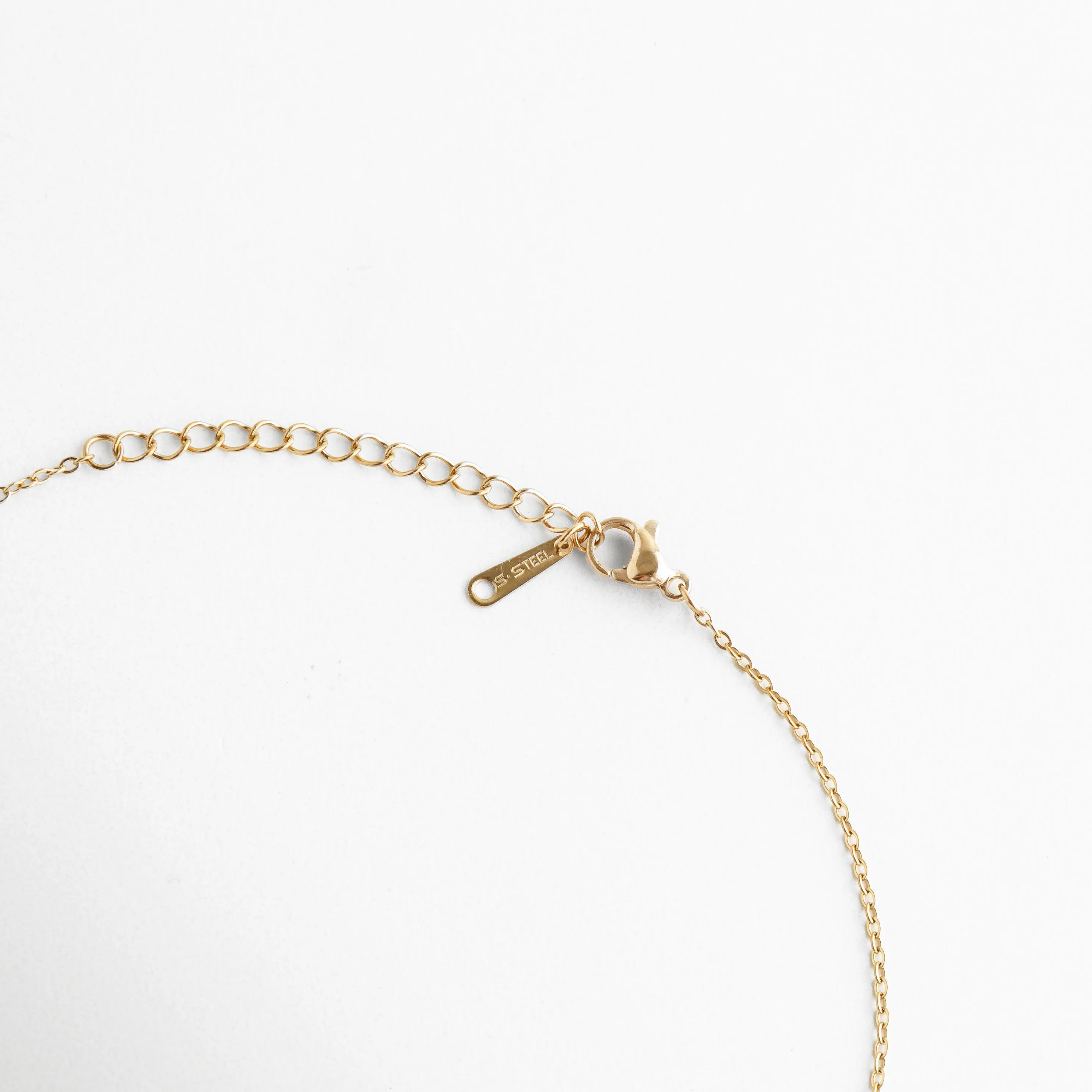 Vista del broche tipo langosta y la cadena de extensión ajustable en acabado dorado, Detalle técnico del sistema de cierre seguro para el collar de elefante de jade, Terminación de la cadena con eslabones de ajuste para diferentes alturas de escote, Cierre de joyería fina resaltando el pulido del baño de oro y la placa de calidad, Muestra del extensor de cadena para personalizar el largo del collar de amuleto.