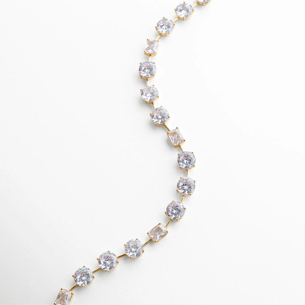 Detalle del collar dorado con cristales transparentes que aportan brillo elegante y sofisticado.