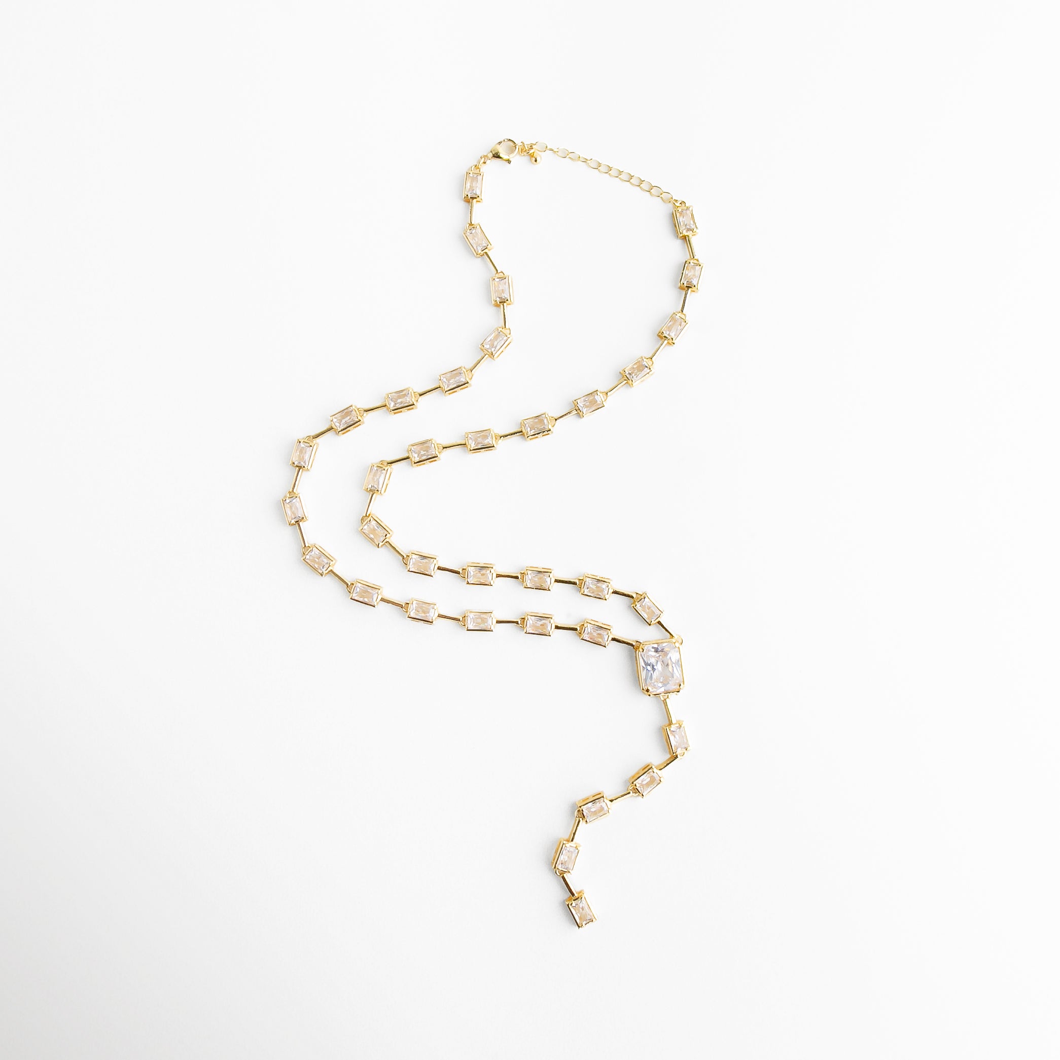 Collar lariat dorado extendido mostrando su silueta alargada y diseño limpio con acabado brillante.