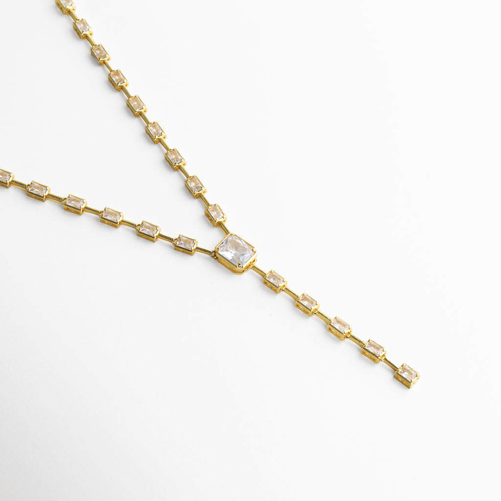 Vista lateral del collar lariat dorado destacando su caída elegante y proporciones equilibradas.