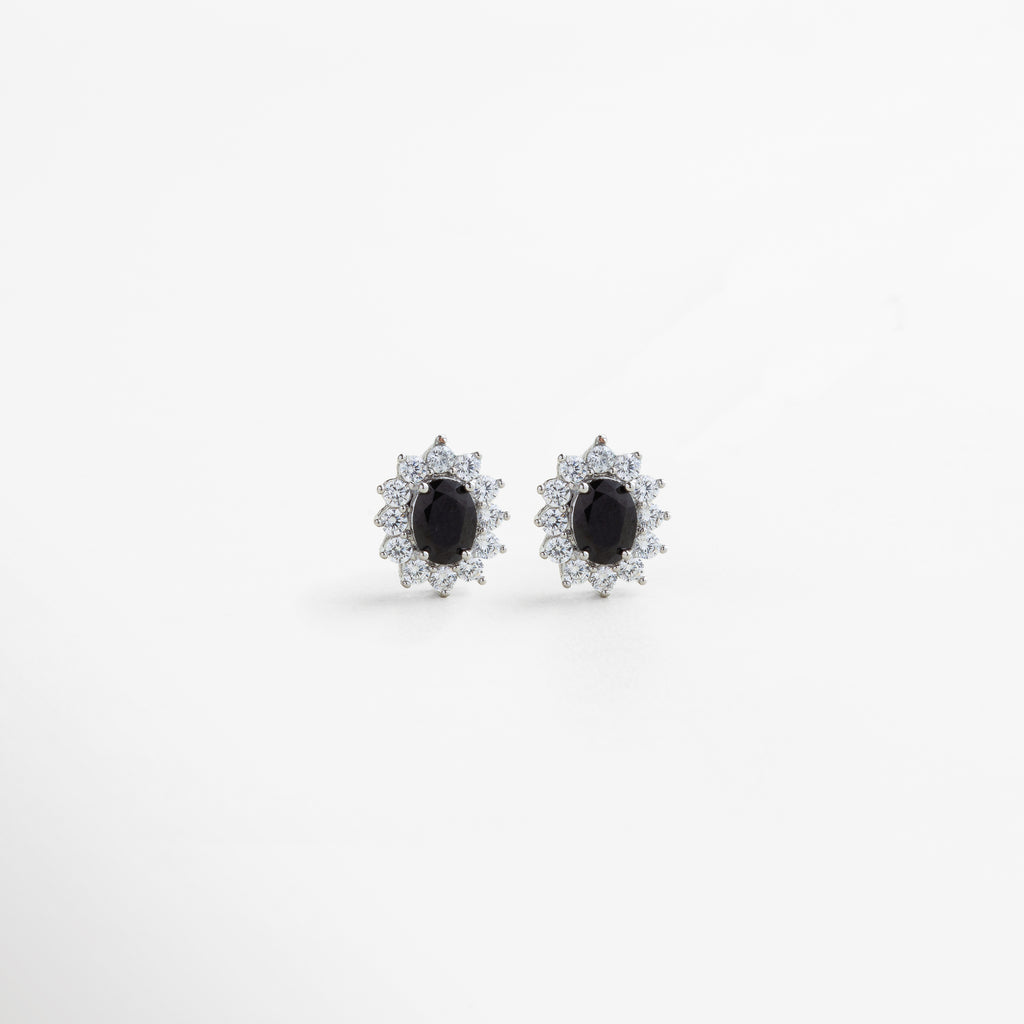 aretes plateados con centro de cristal negro, joya de cobre con baño de plata esterlina y zirconias, aretes elegantes con halo brillante y piedra central oscura, diseño sofisticado en plata con contraste negro, pendientes plateados con detalle central en cristal