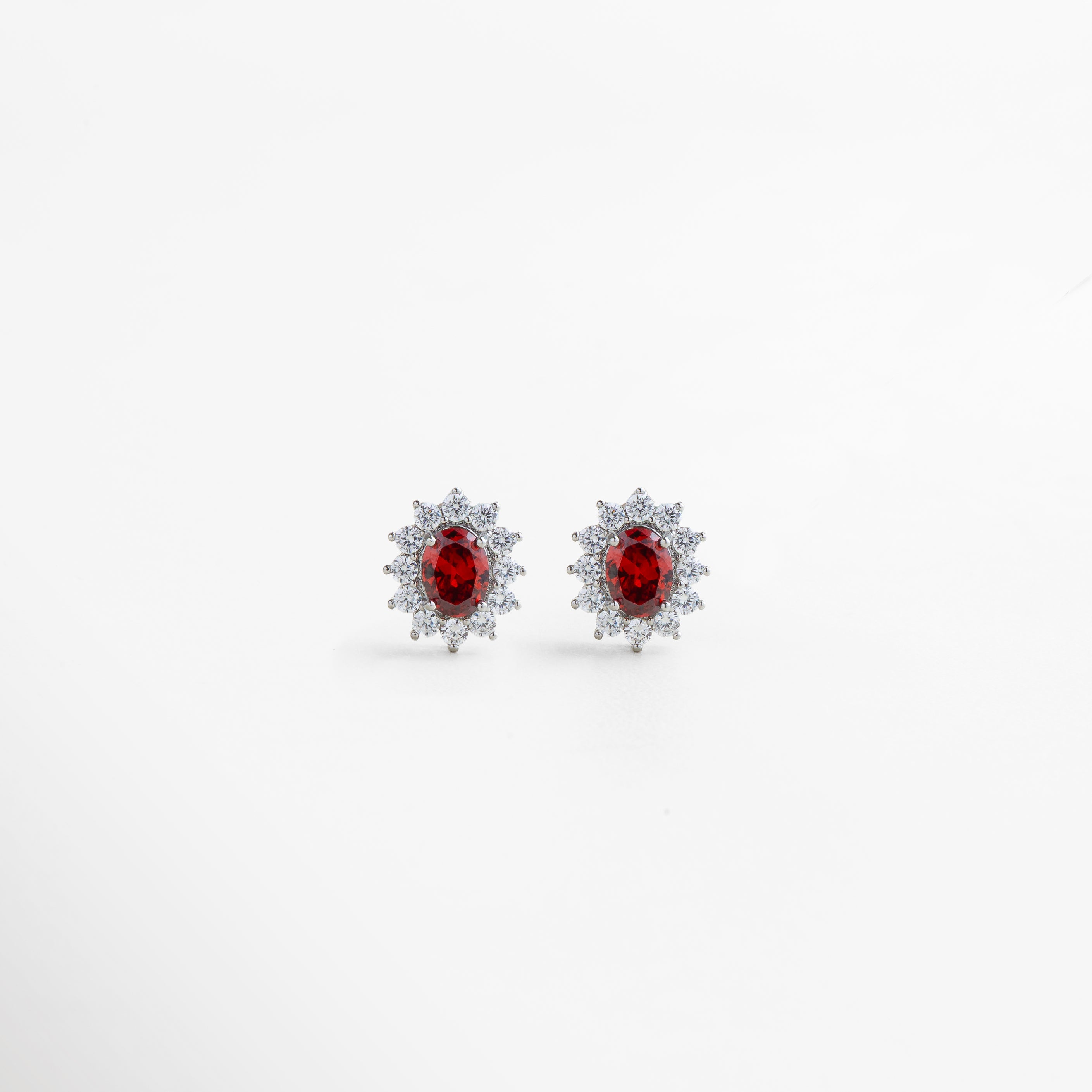 Aretes plateados con cristal rubí en centro y halo de zirconias, diseño romántico y con carácter, joyería sofisticada para dar un toque apasionado a cualquier look