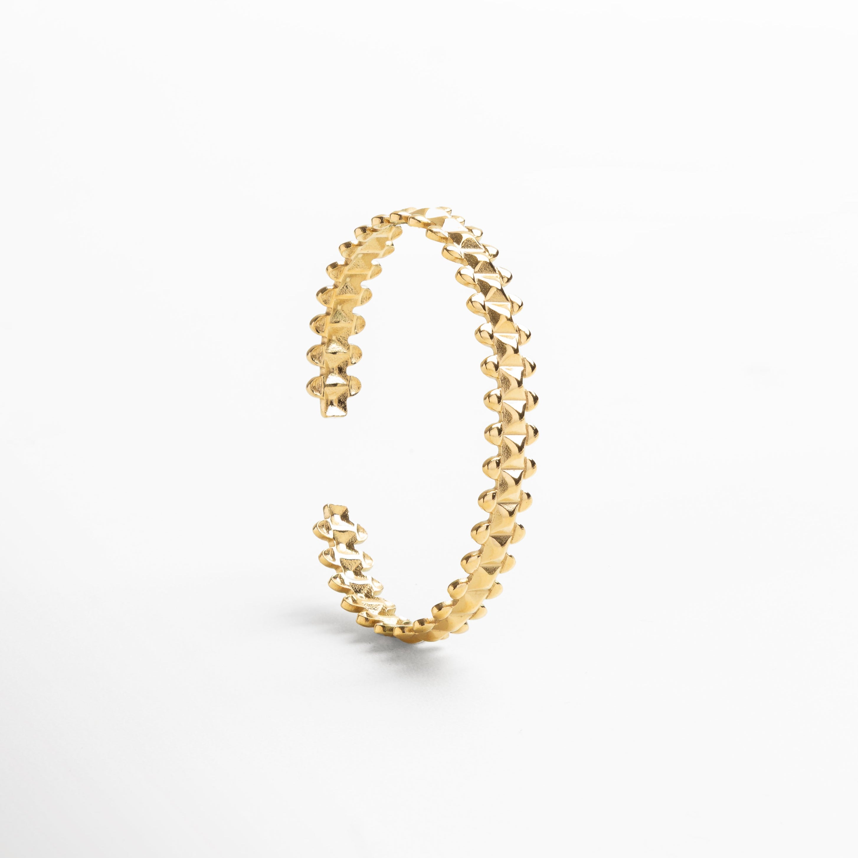 Primer plano del acabado dorado pulido que refleja luz, Detalle del recubrimiento en oro 18K con textura refinado, Diseño ajustable con estructura geométrica definida, Acabado suave que aporta un brillo cálido y sofisticado, Enfoque en las líneas limpias y ángulos delicados