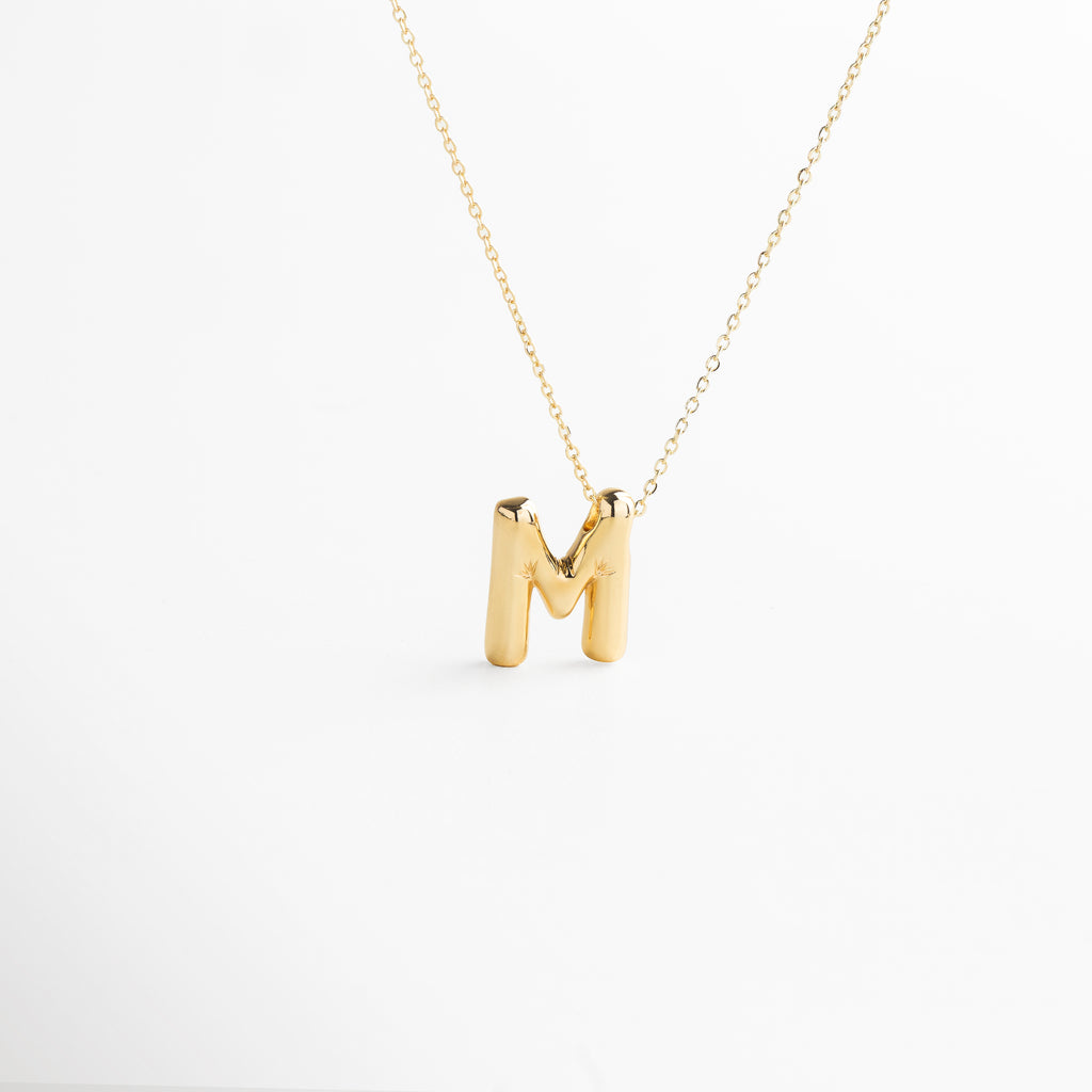 Collar dorado de inicial M con diseño bold y moderno, Inicial M grande en chapa de oro 18K con acabado brillante, Pieza personalizable con significado y estilo atemporal, Letra M central como protagonista del diseño sofisticado, Diseño de cadena fina con punto focal en forma de M
