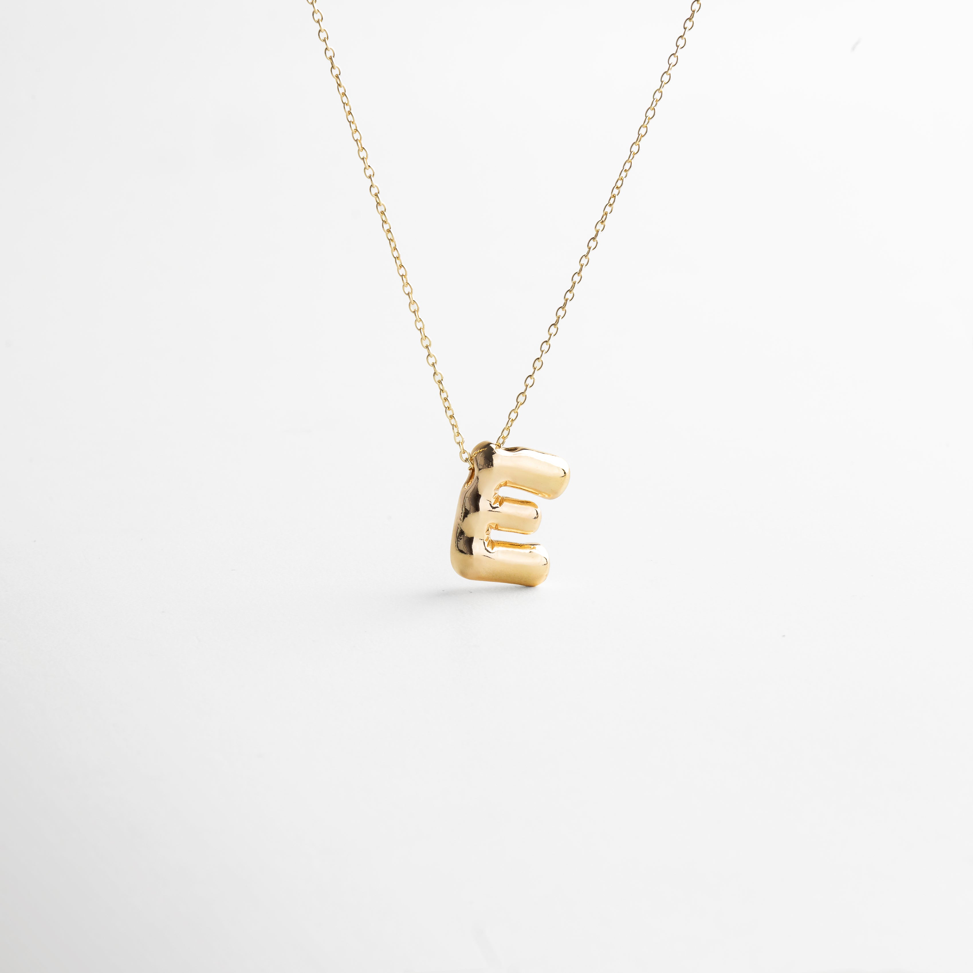Collar dorado de inicial E con diseño bold y moderno, Inicial E grande en chapa de oro 18K con acabado brillante, Pieza personalizable con significado y estilo atemporal, Letra E central como protagonista del diseño sofisticado, Diseño de cadena fina con punto focal en forma de E