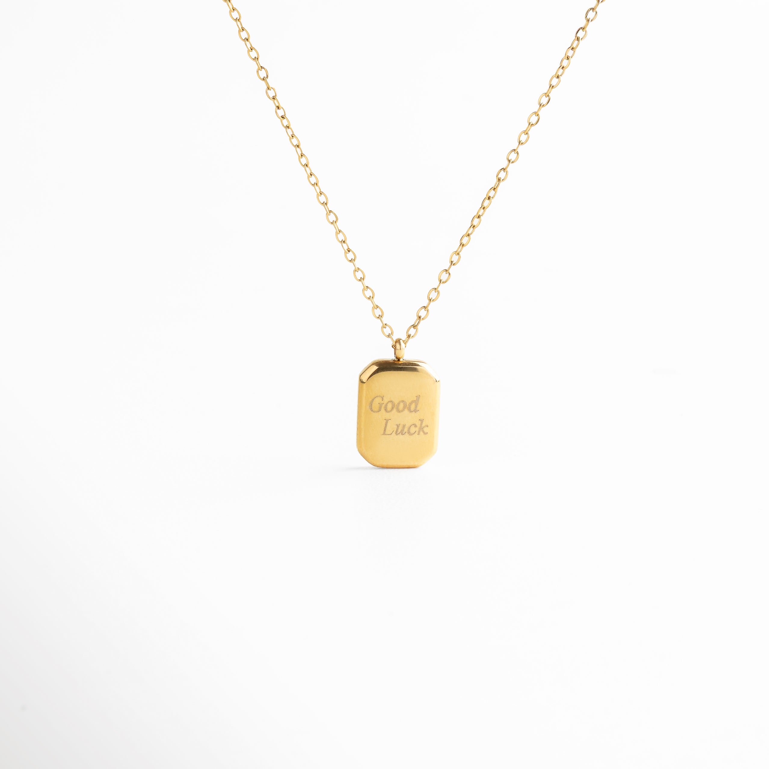 Collar Golden Luck visto de frente, con placa dorada al centro grabada con la palabra “Luck”. Vista frontal del collar con dije rectangular en tono dorado y grabado sutil en el centro. Collar dorado con letrero “Luck” en una placa lisa y brillante, diseño moderno y elegante. Primer plano del Collar Golden Luck con placa central rectangular y cadena delgada. Collar dorado con diseño minimalista y grabado central “Luck”, visto desde el frente sobre fondo neutro.