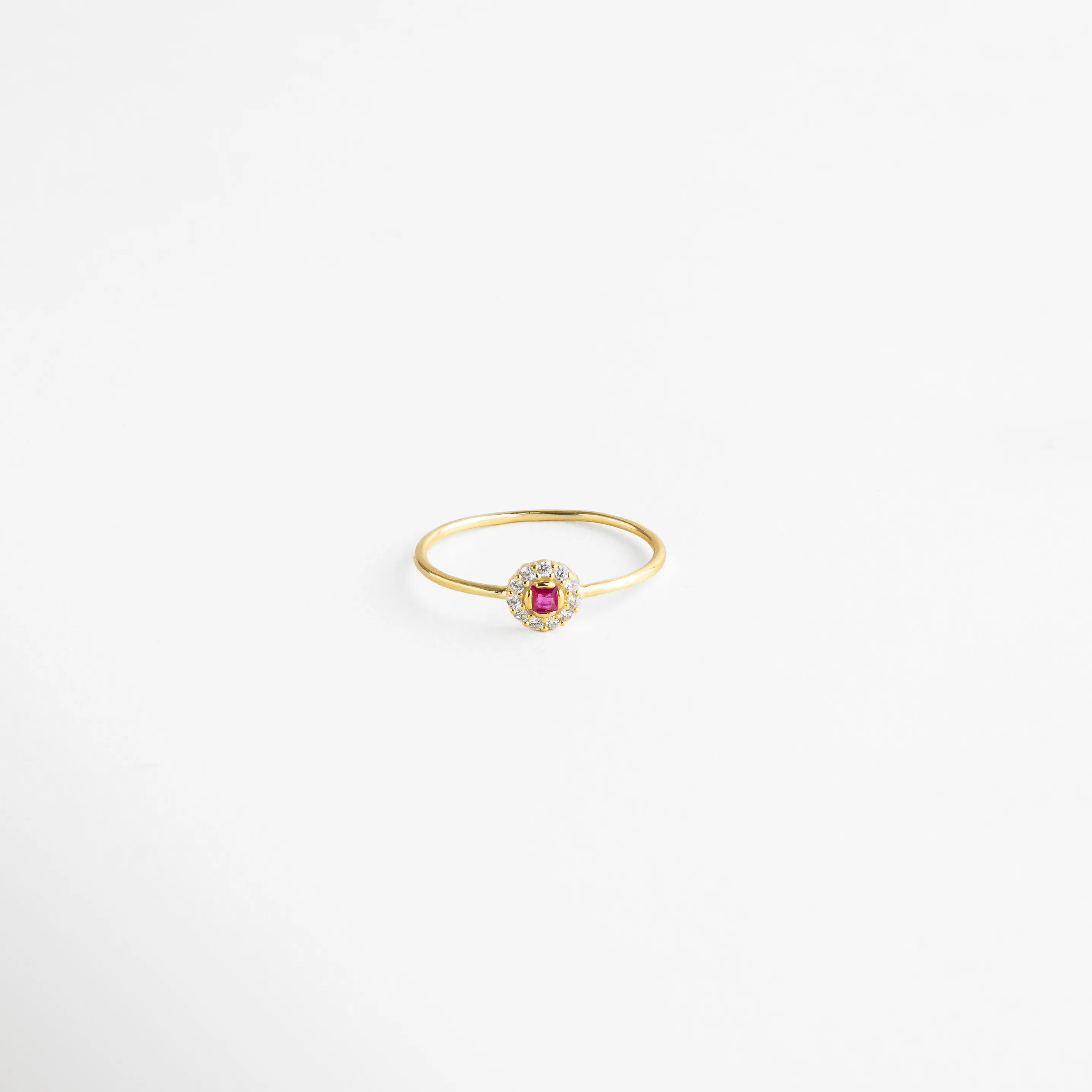 Anillo dorado con centro de piedra fucsia rodeada de cristales transparentes, un diseño delicado y femenino.