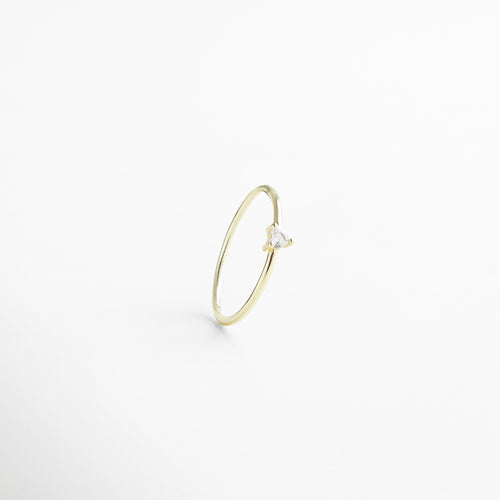 Anillo dorado delgado visto de frente, con pequeña piedra en forma de corazón en el centro. Vista frontal del anillo Heart dorado, diseño delicado y romántico sobre fondo neutro. Anillo fino en tono dorado con piedra central en forma de corazón, fotografía frontal completa. Primer plano frontal del anillo Heart dorado, destacando su piedra central y acabado elegante. Anillo dorado con piedra en forma de corazón, visto de frente con diseño sutil y femenino.