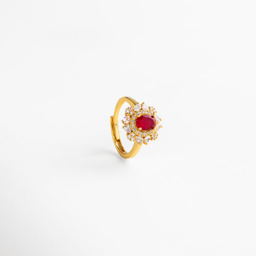 Vista lateral del anillo en cobre con baño de oro 18K, piedra roja central en forma ovalada rodeada de zirconias cúbicas transparentes, diseño ajustable de estilo atemporal con acabado pulido que aporta elegancia y fuerza a cualquier look.