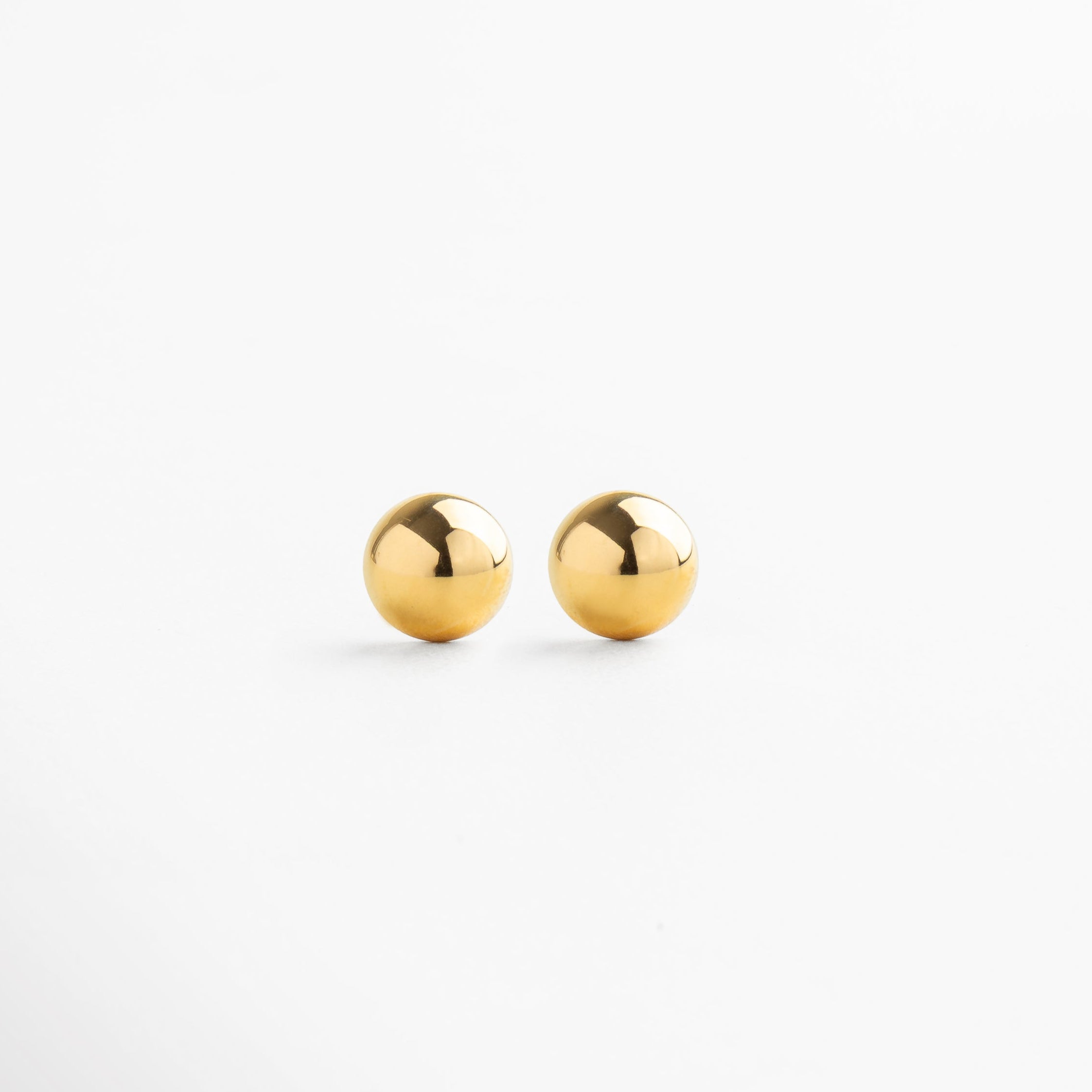 Aretes minimalistas de media bolita dorada, diseño simple y elegante, joyería delicada para uso diario, accesorio sutil que aporta sofisticación y estilo atemporal