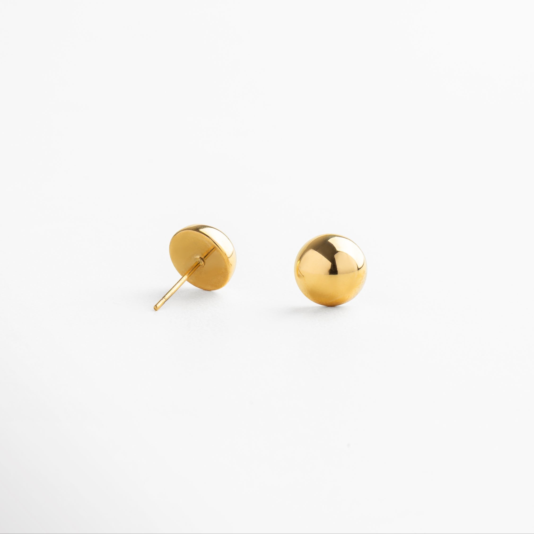 Detalle de aretes con media bolita dorada de acabado liso, pieza pequeña y refinada que añade un toque discreto y moderno a cualquier look casual o formal