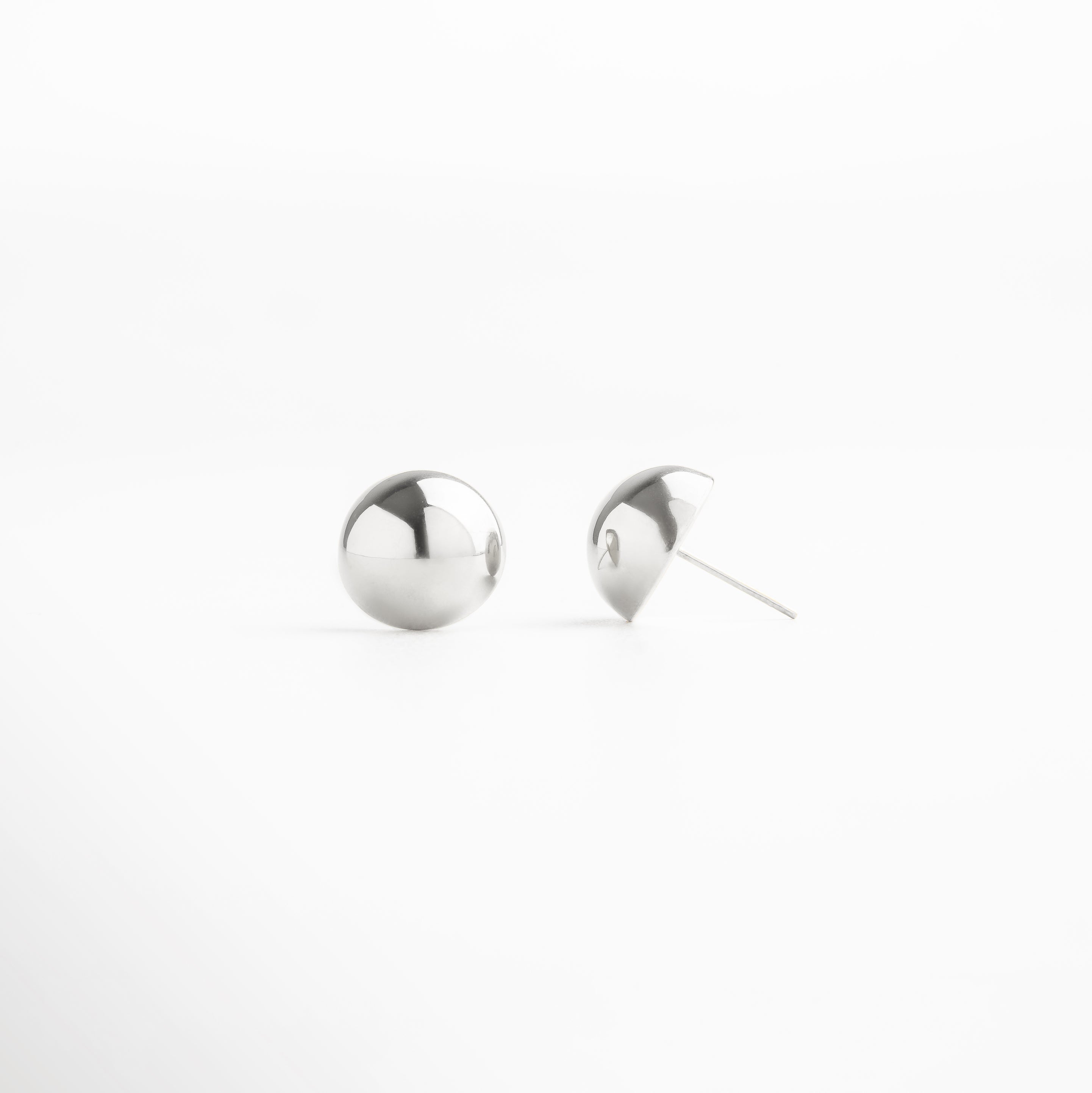 Vista lateral de aretes de acero inoxidable en forma de esfera plateada, estilo clásico y sofisticado, perfectos como accesorios versátiles para uso diario.