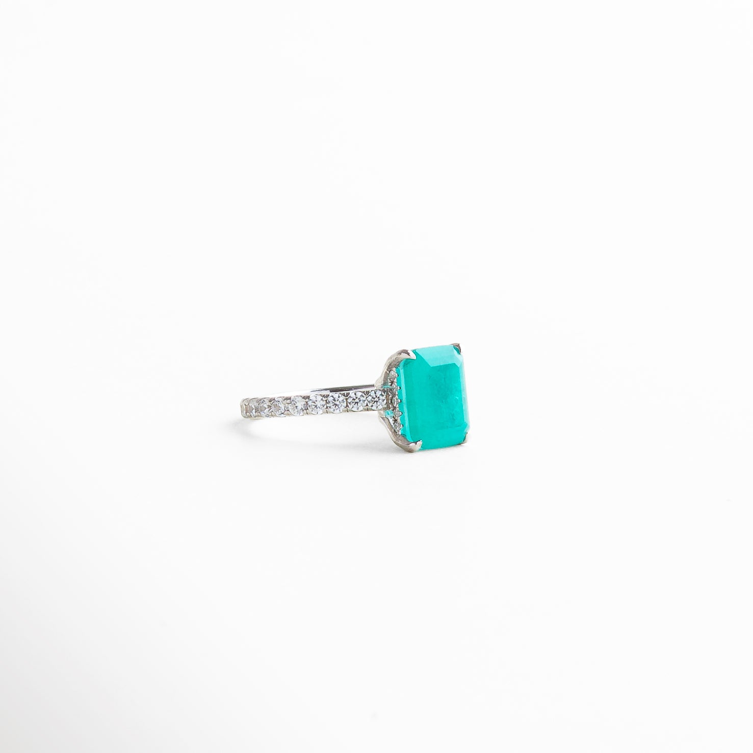 Acercamiento a la textura del anillo y la disposición de las piedras, destacando cómo el diamante y las gemas capturan la luz creando destellos refinados