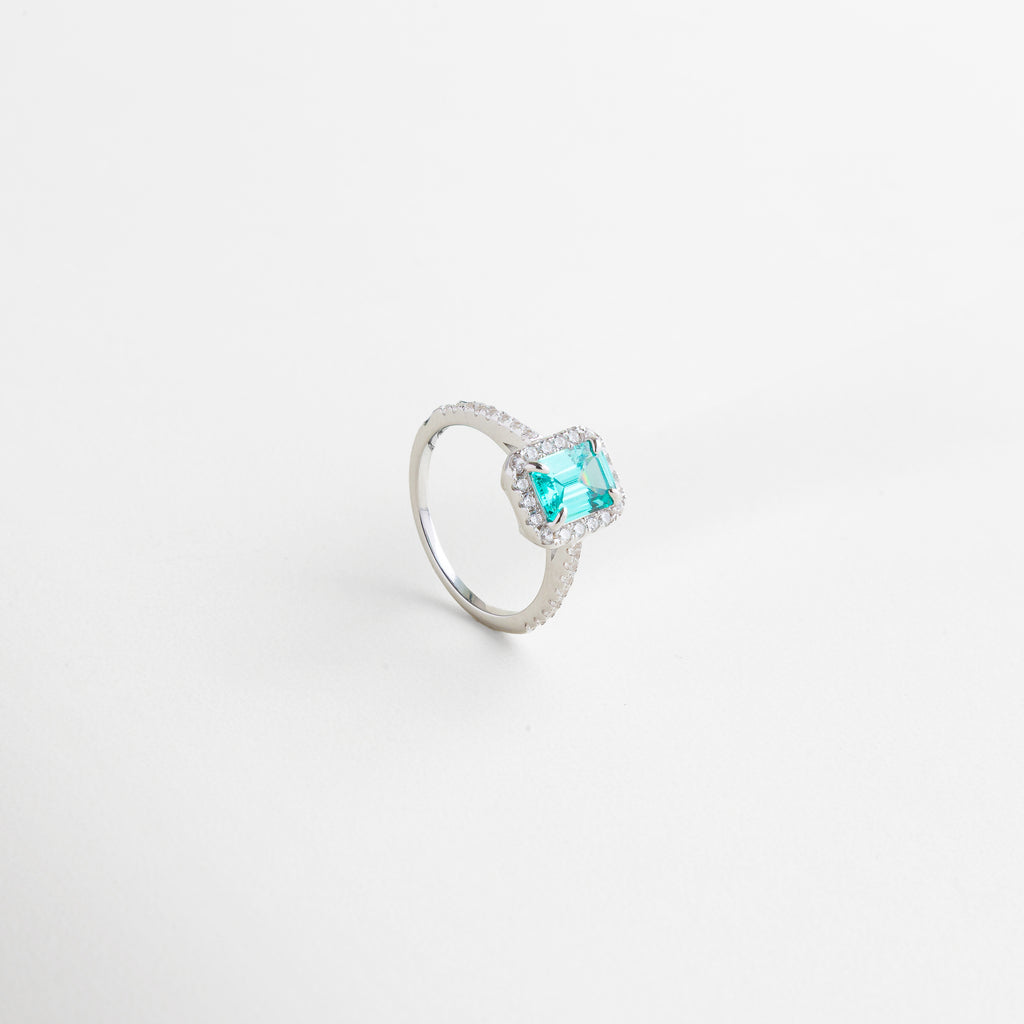 Acercamiento al borde de zirconias que enmarca la piedra, Perfil del anillo mostrando su altura y estructura, Lateral con acabado pulido en oro blanco 18K, Diseño delicado con presencia sofisticada, Detalles de la talla precisa de las zirconias