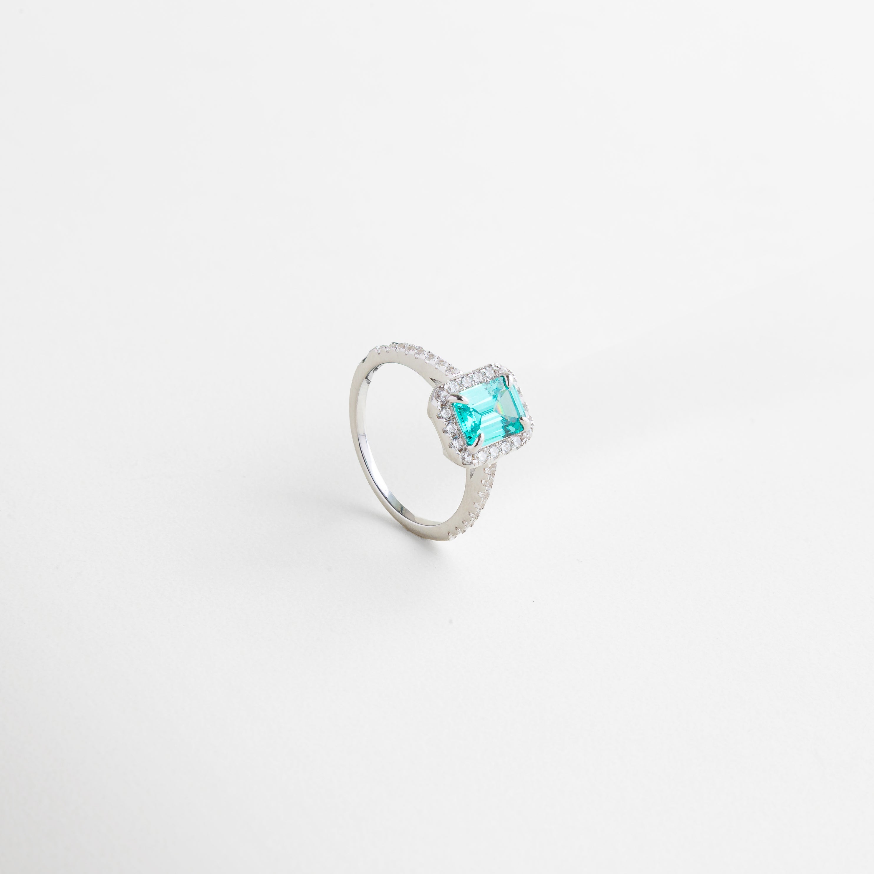 Acercamiento al borde de zirconias que enmarca la piedra, Perfil del anillo mostrando su altura y estructura, Lateral con acabado pulido en oro blanco 18K, Diseño delicado con presencia sofisticada, Detalles de la talla precisa de las zirconias